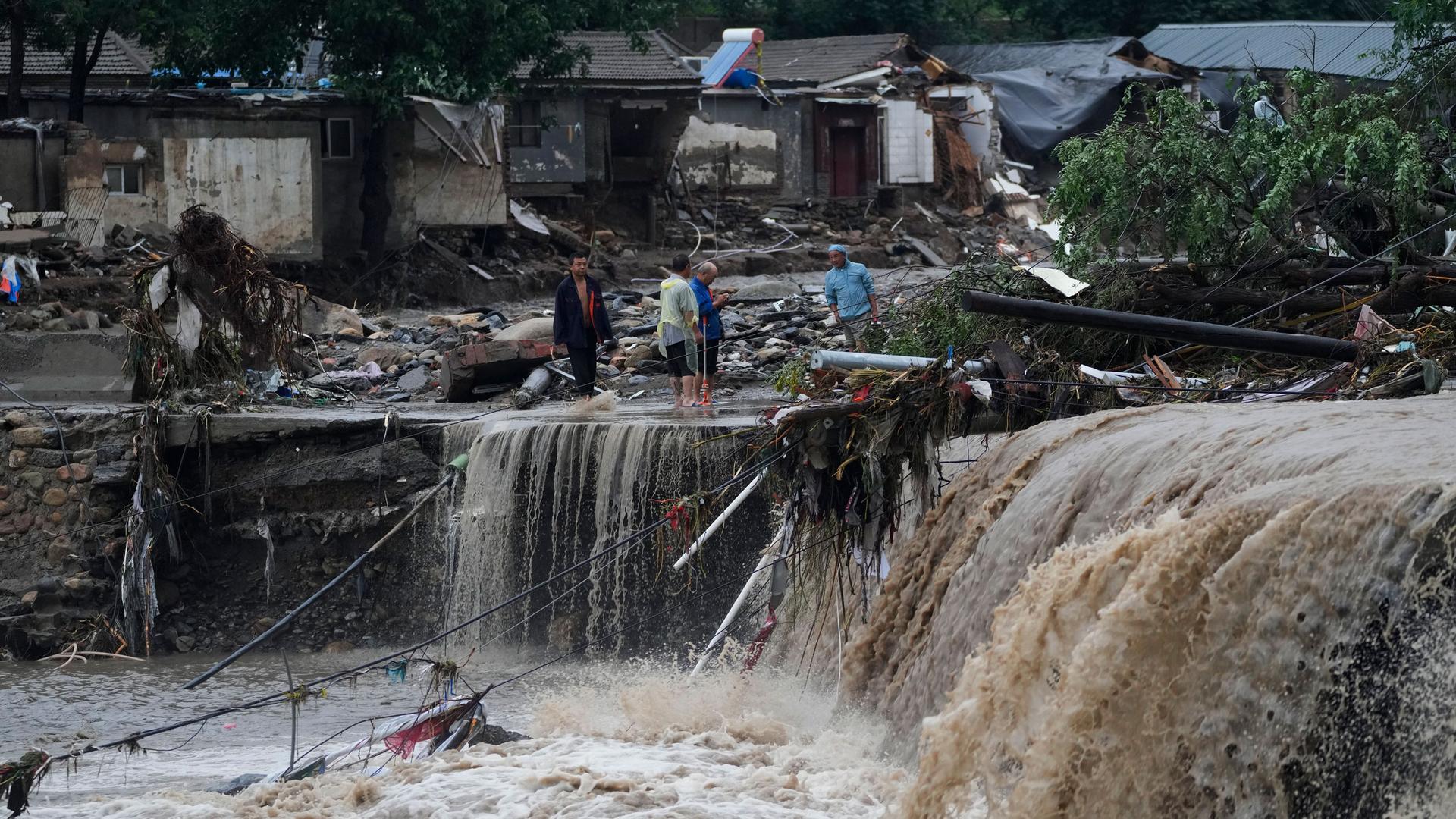 Villagers gather near a village damaged by floodwaters in the Mentougou District as continuous rain fall triggers alerts in Beijing, Monday, July 31, 2023. 