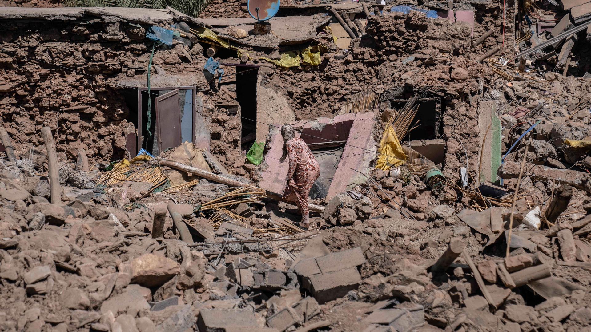 A woman tries to recover some of her possessions from her home which was damaged by an earthquake in the village of Tafeghaghte, near Marrakech, Morocco, Monday, Sept. 11, 2023.