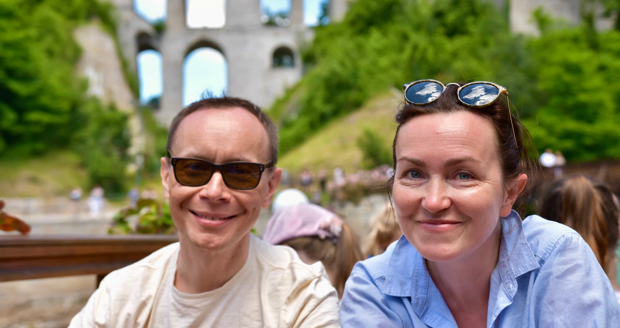 A man wearing sunglasses smiling next to a woman with sunglasses on her head