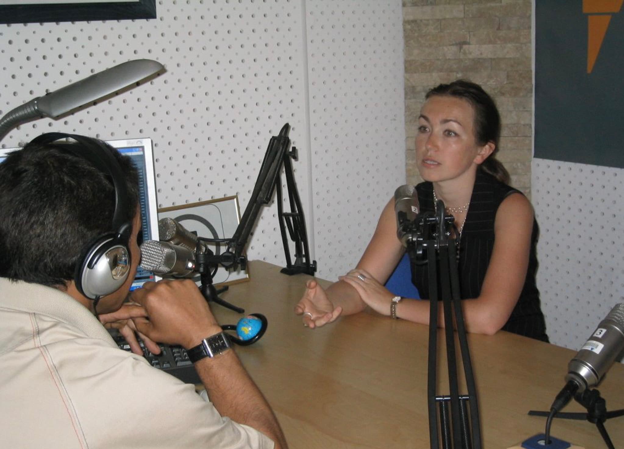 A man and woman sitting behind audio mics