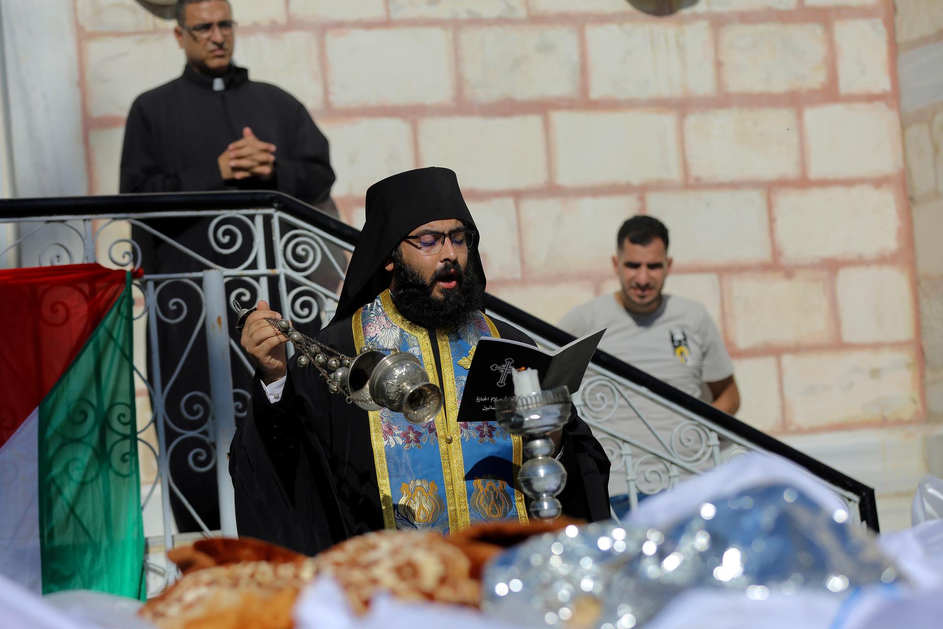 A priest holds a funeral service for Palestinians who were killed in Israeli airstrikes that hit a church, in Gaza City, Oct. 20, 2023.