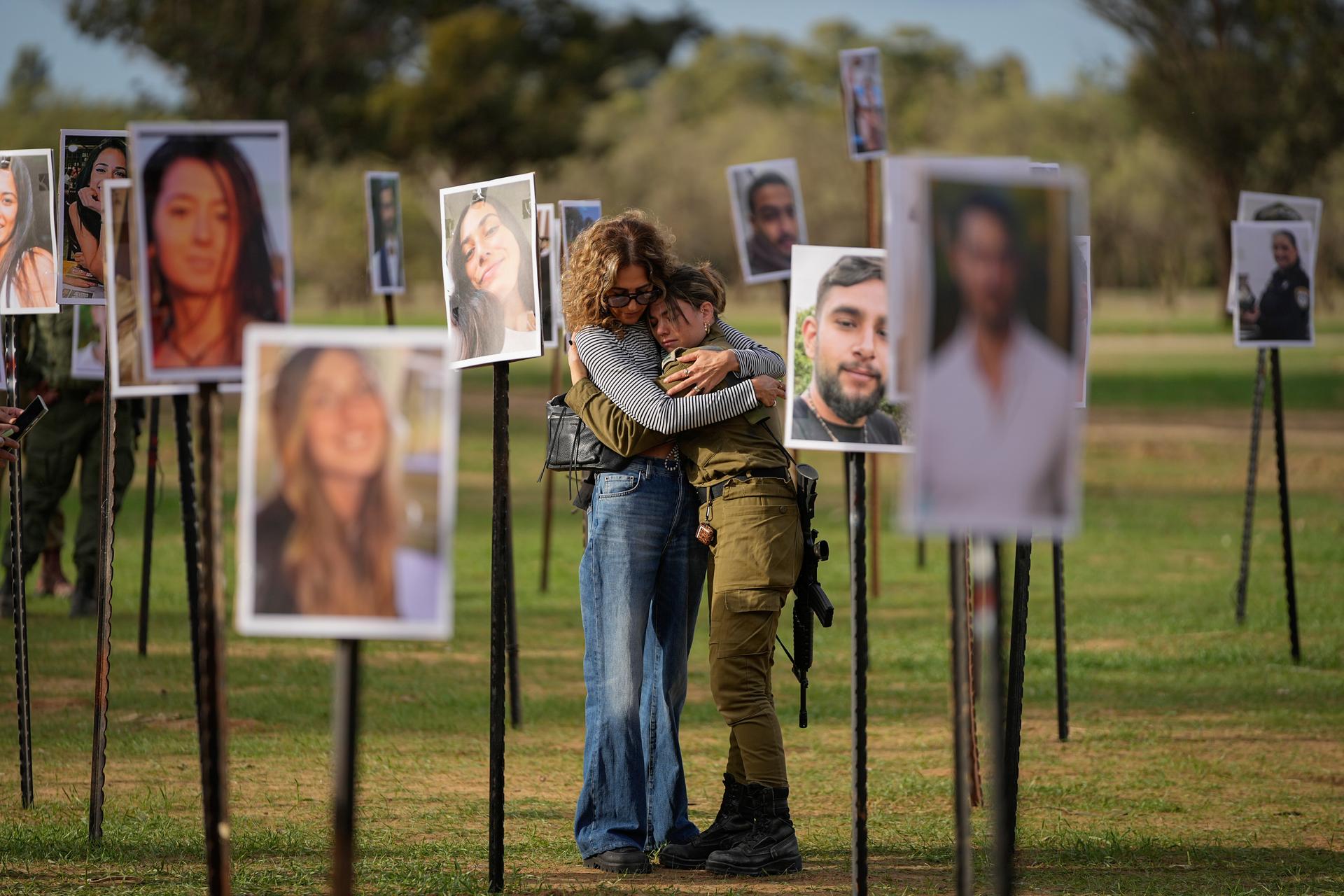 Israelis embrace next to photos of people killed and taken captive by Hamas, Nov. 28, 2023.