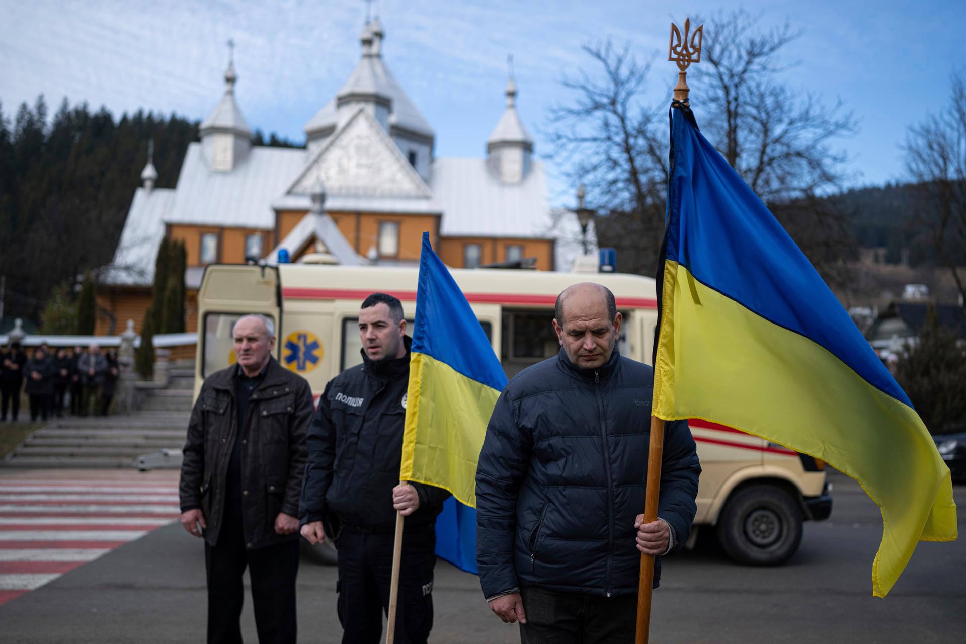 People hold Ukrainian flags during the funeral ceremony of the killed Vasyl Medviychuk and Dmytro Dosiak Ukrainian army offices in Verkhovyna, Ukraine, Dec. 28, 2023.