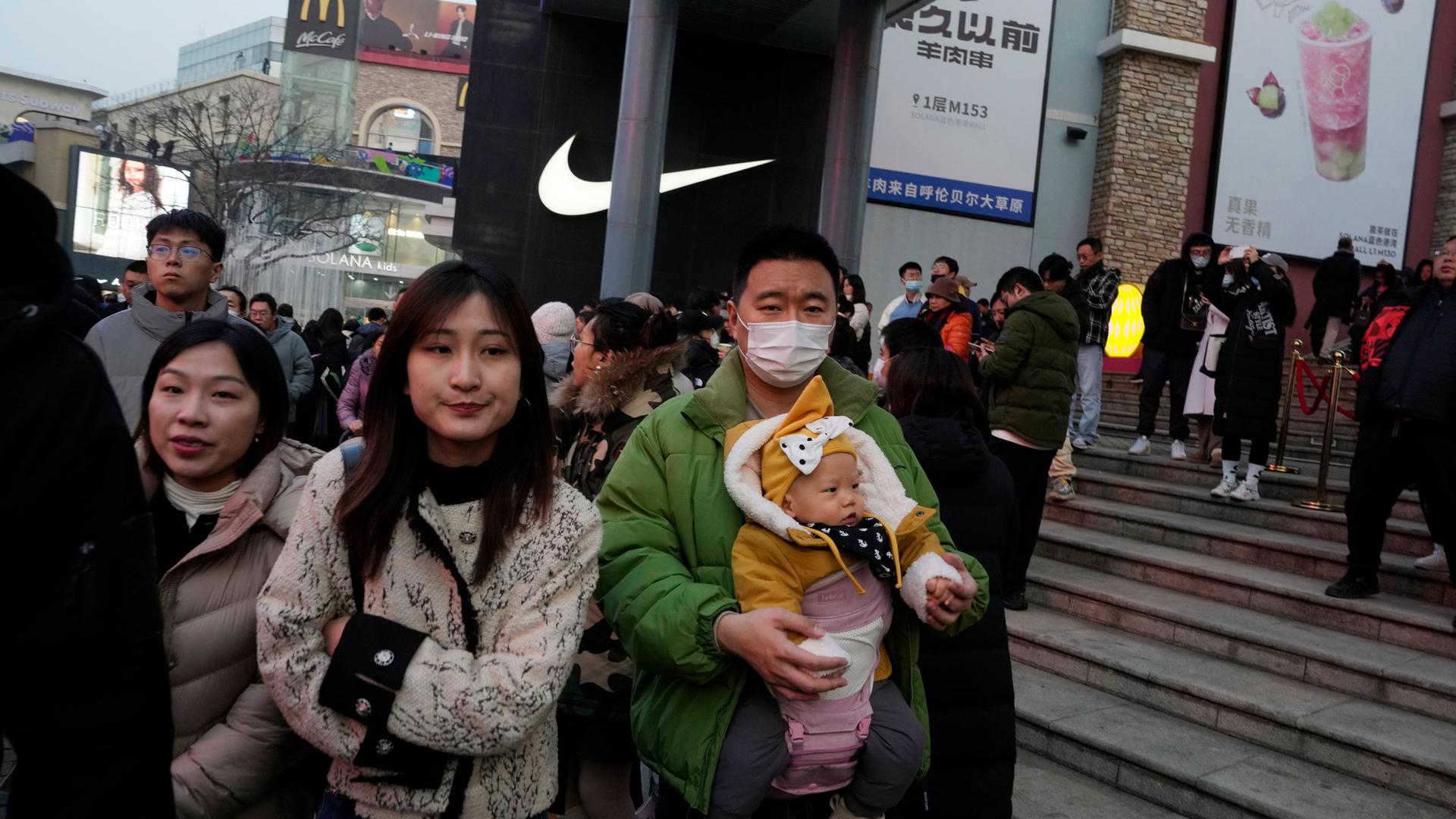 A man carries a child at a shopping mall in Beijing, Dec. 30, 2023. China’s population dropped by 2 million people in 2023 in the second straight annual drop as births fell and deaths jumped. 