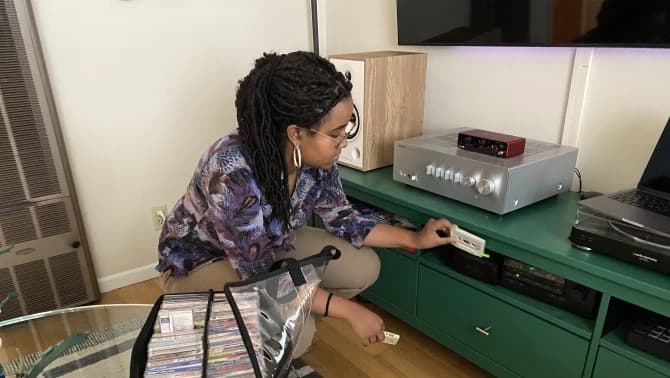 A girl with braided hair kneeling down with tapes in hand
