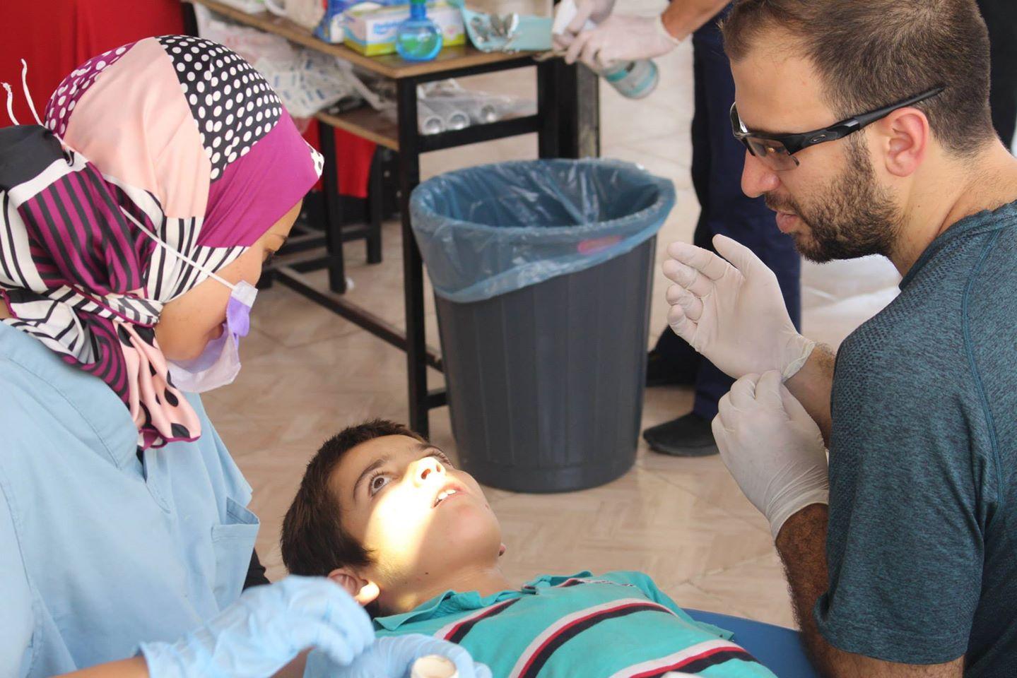 Whether to say "needle" or "sleepy juice": Dr. Sarah Aref and Farris Barakat help a Syrian boy at the temporary Syrian American Medical Society dental clinic on the Turkish-Syrian border.