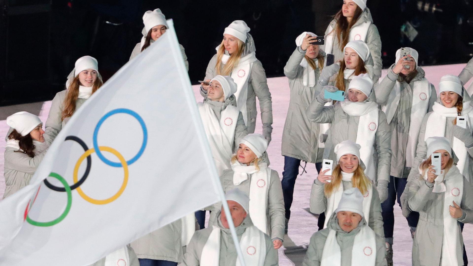People dressed in white carry the Olympic flag instead of the Russian flag.