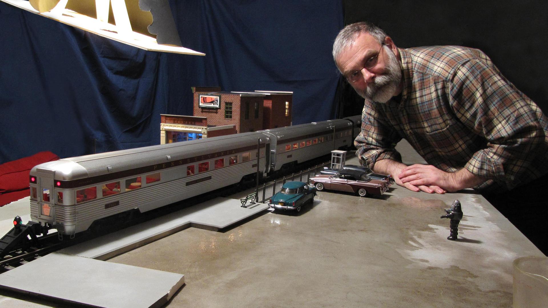 Model-maker Michael Paul Smith poses with a model of a passenger train.