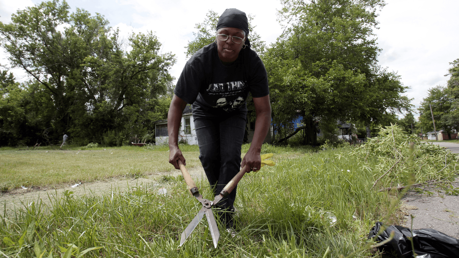 Rhonada Collier clears away tree branches in front of an abandoned house in an attempt to make her once thriving working-class neighborhood that is now littered with blight look better in Flint, Michigan.