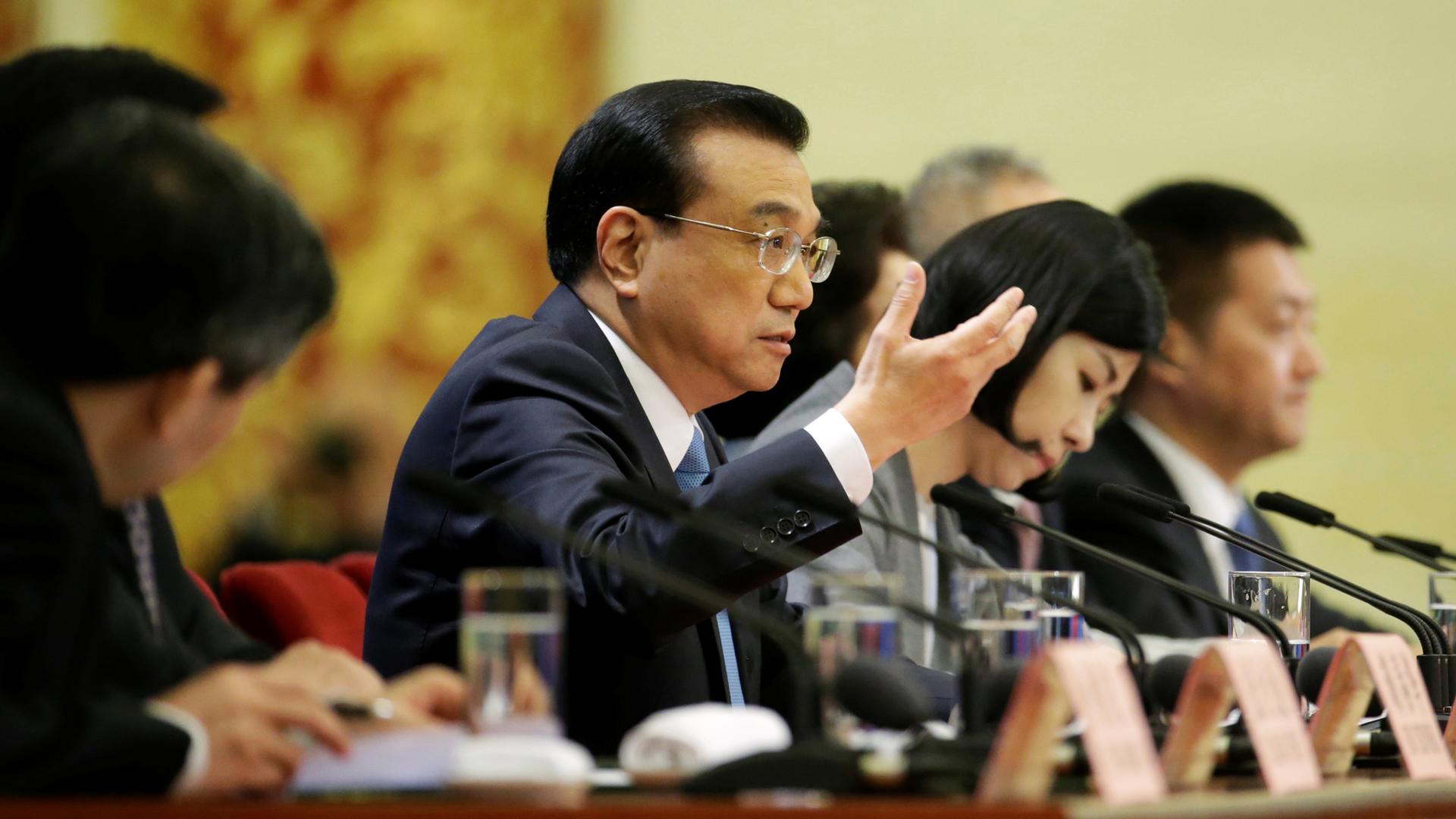 Chinese Premier Li Keqiang speaks at a table lined with microphones during a news conference in Beijing.