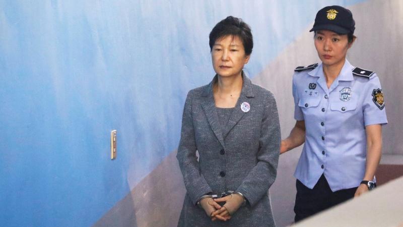 South Korean ousted leader Park Geun-hye arrives at a court in Seoul in handcuffs and escorted by a police officer.