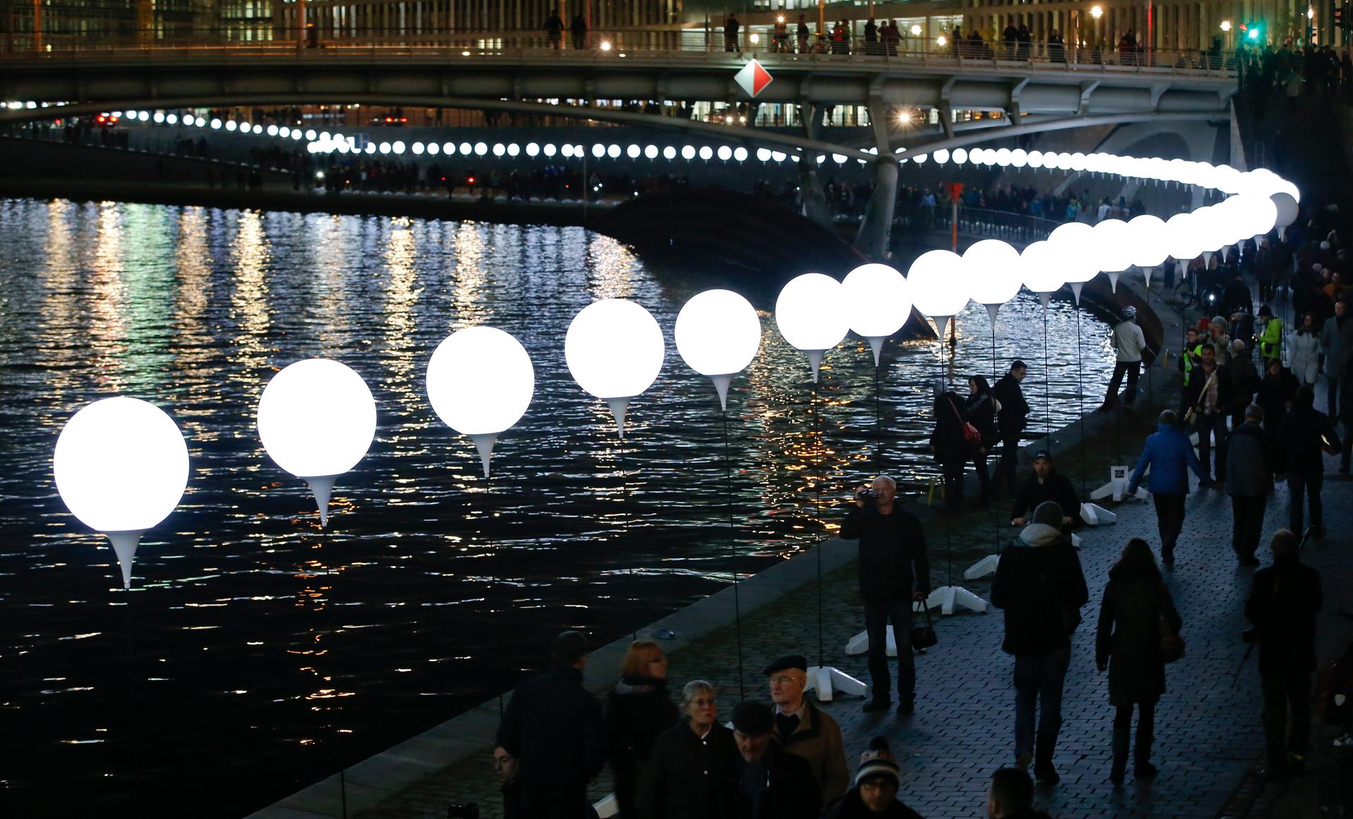 People walk under the "Lichtgrenze" installation along the River Spree in Berlin on November 8, 2014. A part of the inner city of Berlin was temporarily divided with a light installation to commemorate the 25th anniversary of the fall of the Berlin Wall.