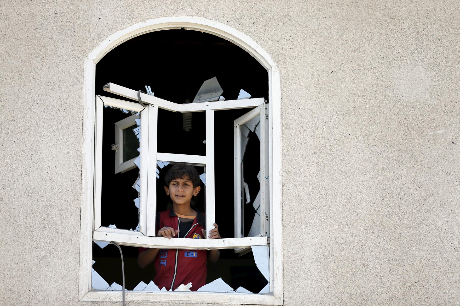 A boy looks through a window of his home damaged by an air strike near Sanaa Airport March 31, 2015.
