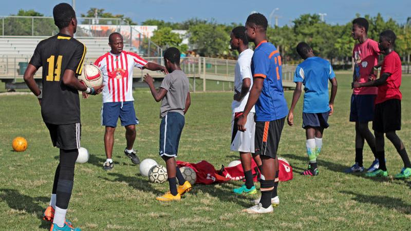 Ernst Baptiste, coach of the Little Haiti Football Club boys team, directs his players onto the field to start drills.
