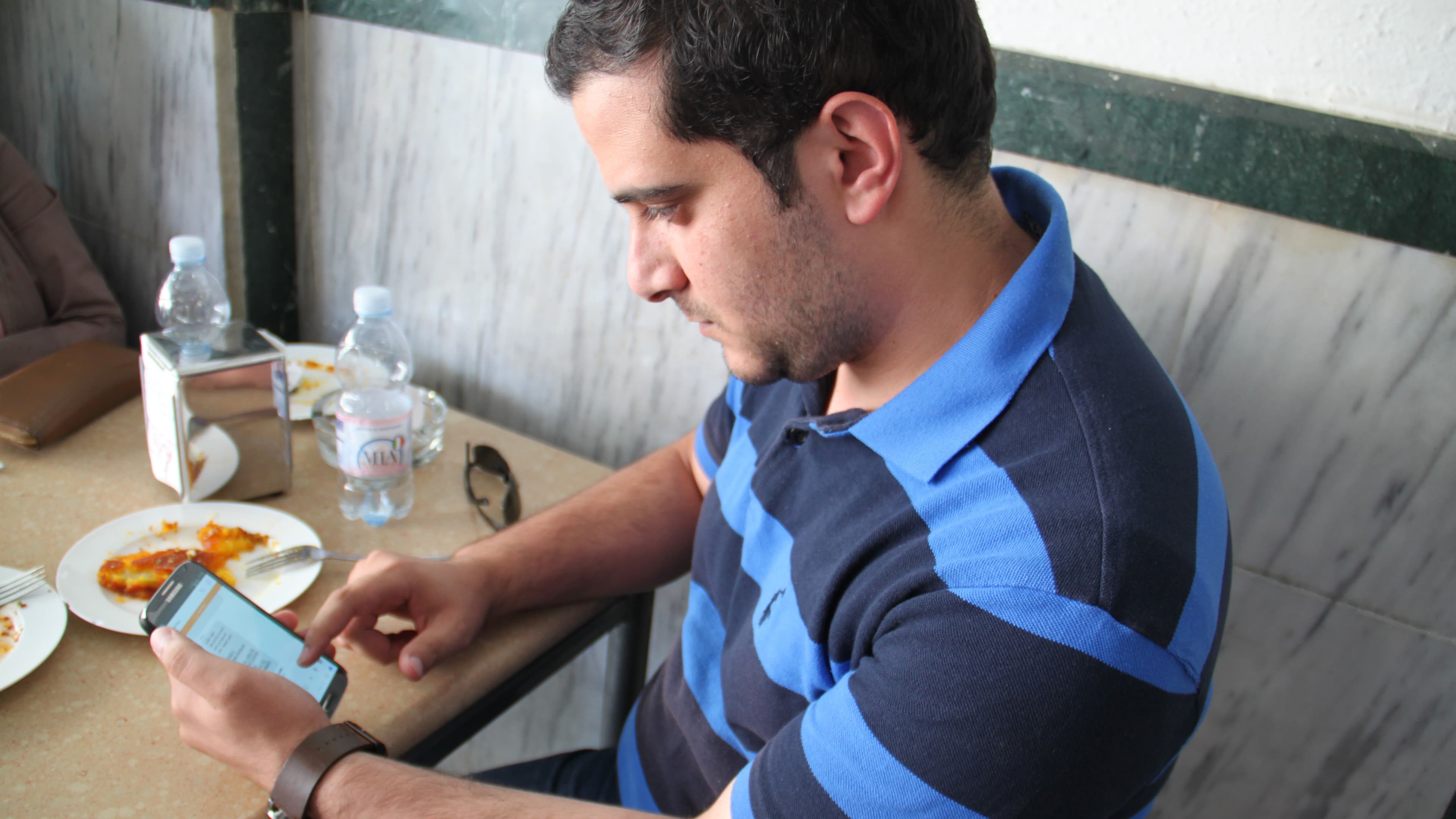 Ahmed Yousef, 25, an editor at Quds News Network, at a sweet shop in Ramallah. A photo of the Dome of the Rock, a sensitive holy site in Jerusalem, is on the wall. Tensions around the site helped spark the recent violence between Israelis and Palestinians