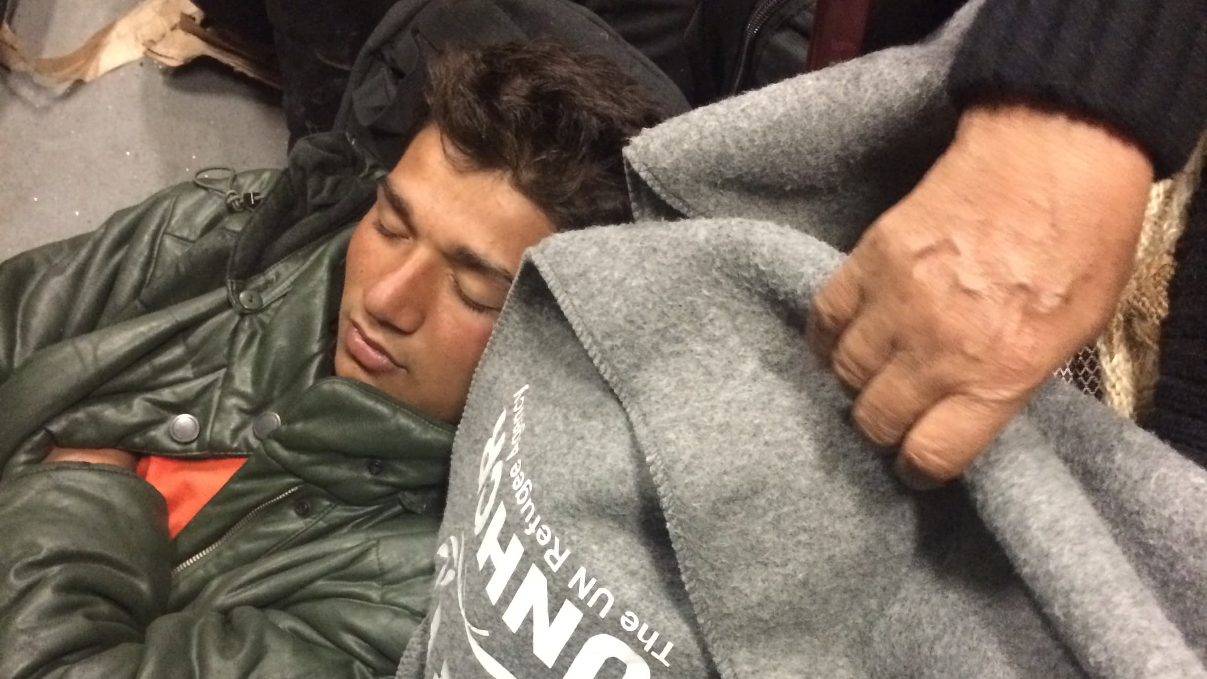A young refugee sleeps as he waits for his bus to take off from a detention center in Hungary.