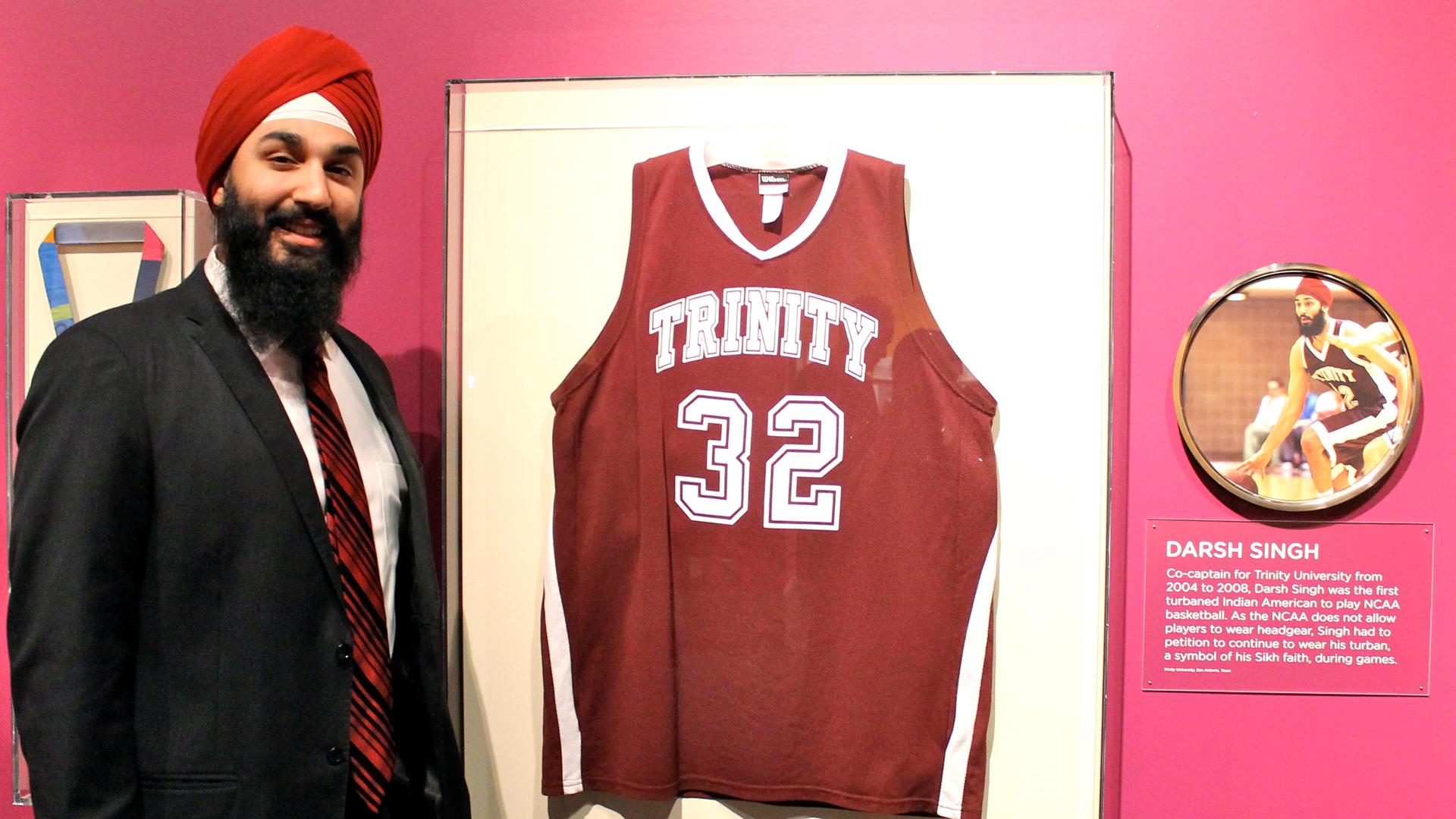 Darsh Preet Singh stands next to his college basketball jersey on display at the Smithsonian's National Museum of Natural History, part of an exhibition on Indian-Americans. Singh is the first Sikh American to play basketball in the NCAA while wearing his