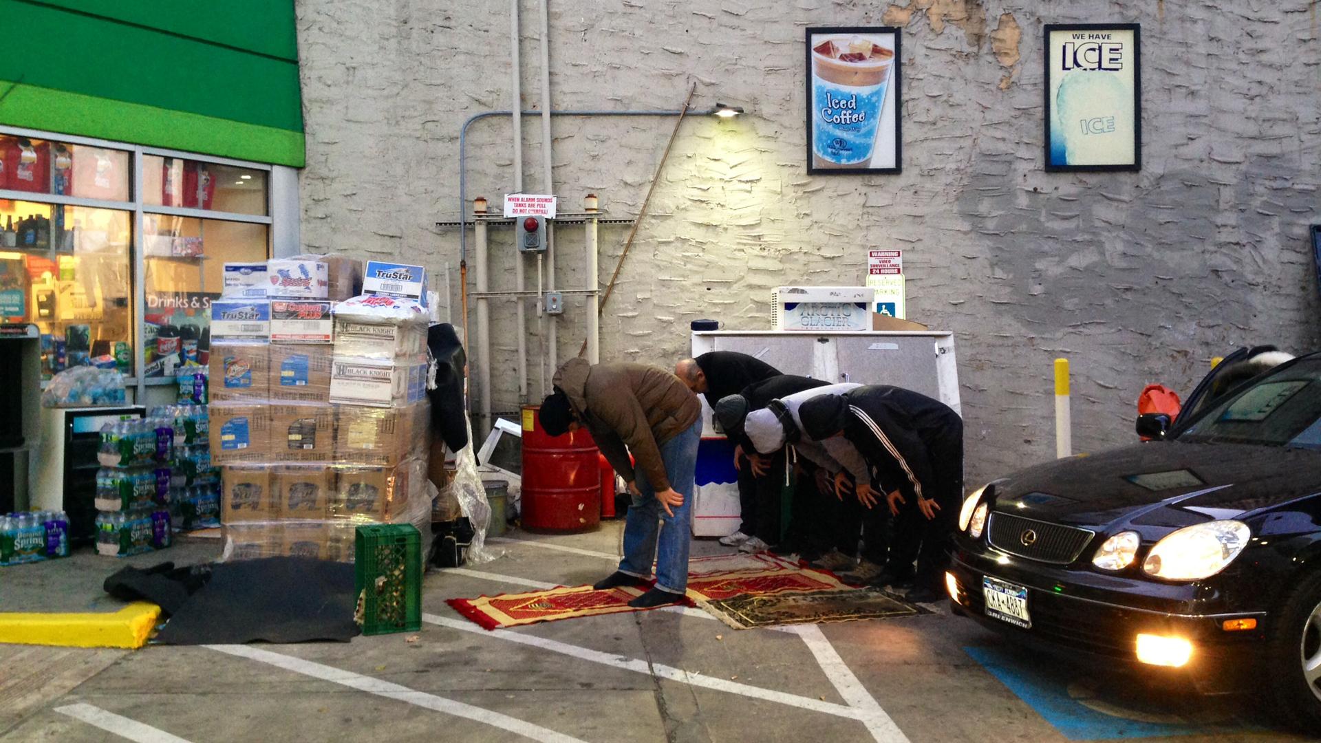 Muslim cabbies pray at a BP station in downtown Manhattan while patrons pump gas.