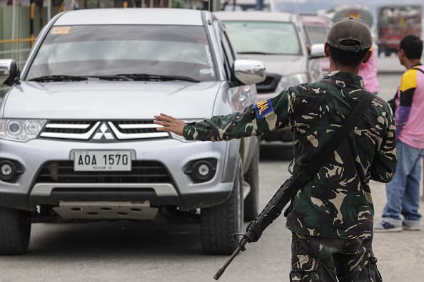 Military personnel stop a vehicle for inspection.