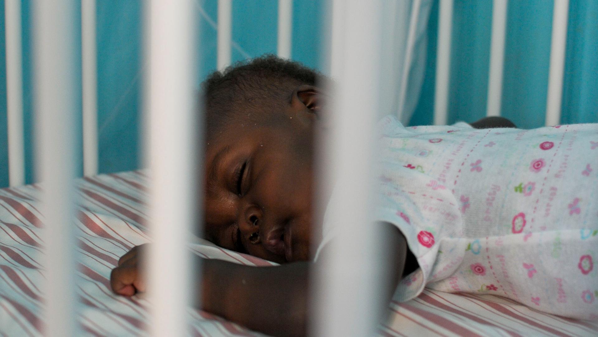 A Haitian child who will be placed for adoption sleeps in his crib at an orphanage outside of Port-au-Prince.