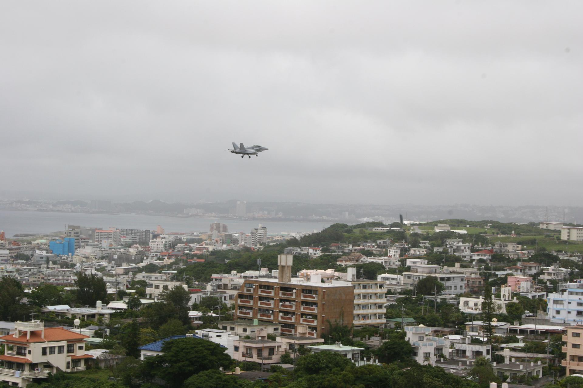 A US military aircraft prepares to land on a runway at the Futenma military base, adjacent to a densely populated city on Okinawa island.