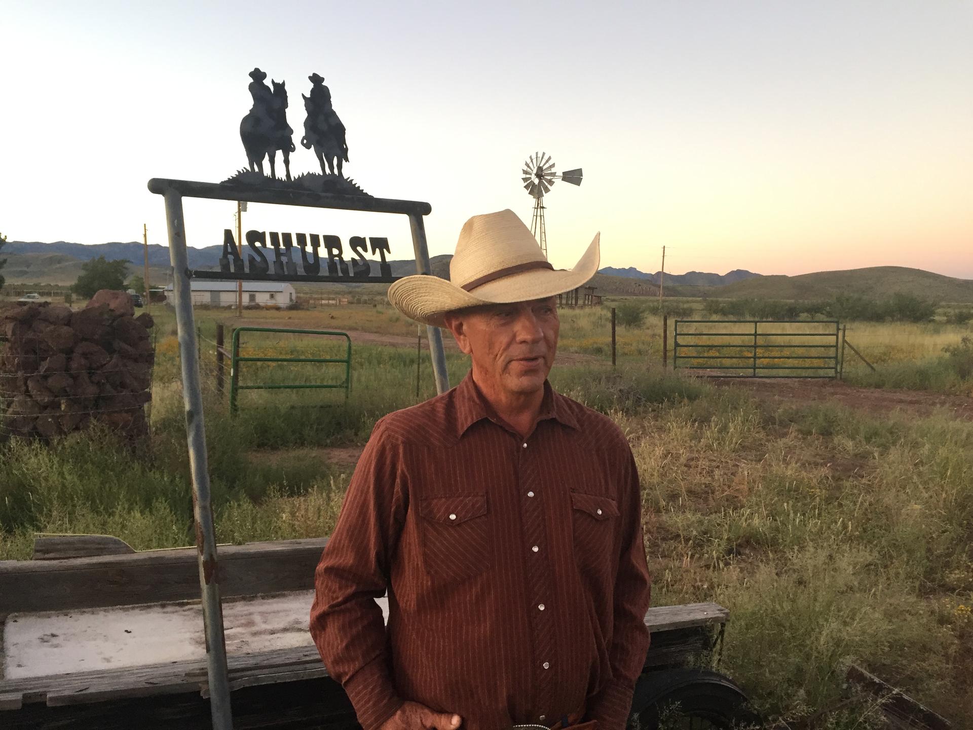 Man standing in front of ranch sign and American flag