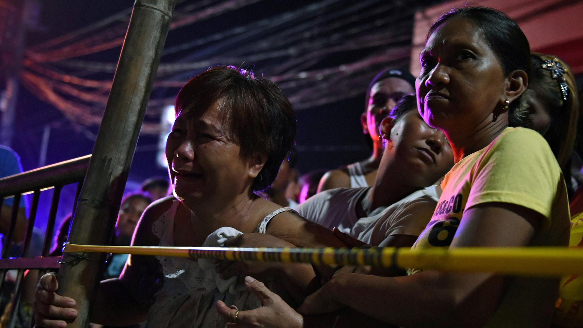 A relative of a victim cries behind the police line at the site of a recent drug-related shooting by unidentified men riding on motorcycles in Manila.