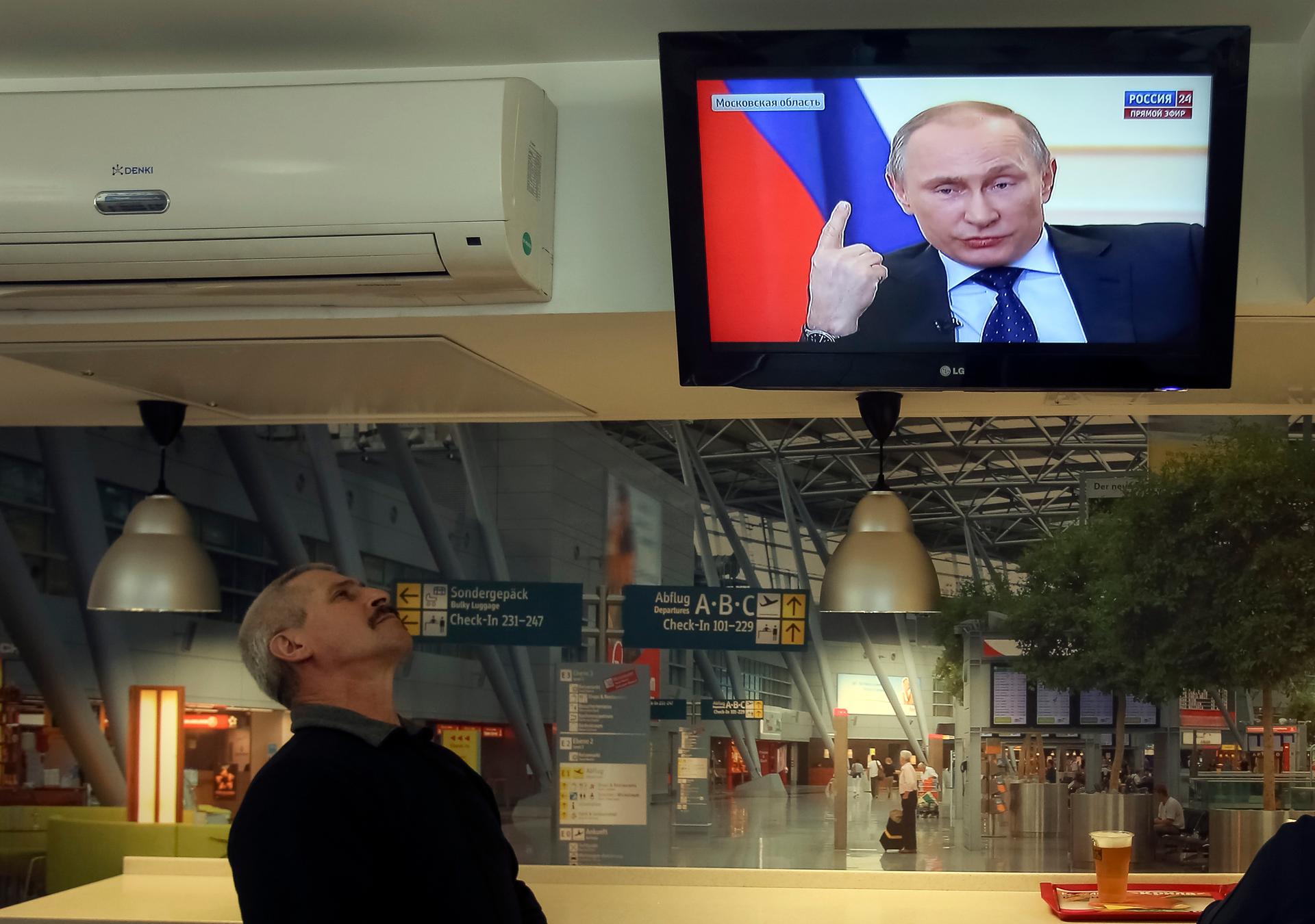 A local resident watches a TV broadcast of Russian President Vladimir Putin's news conference, in Kiev.