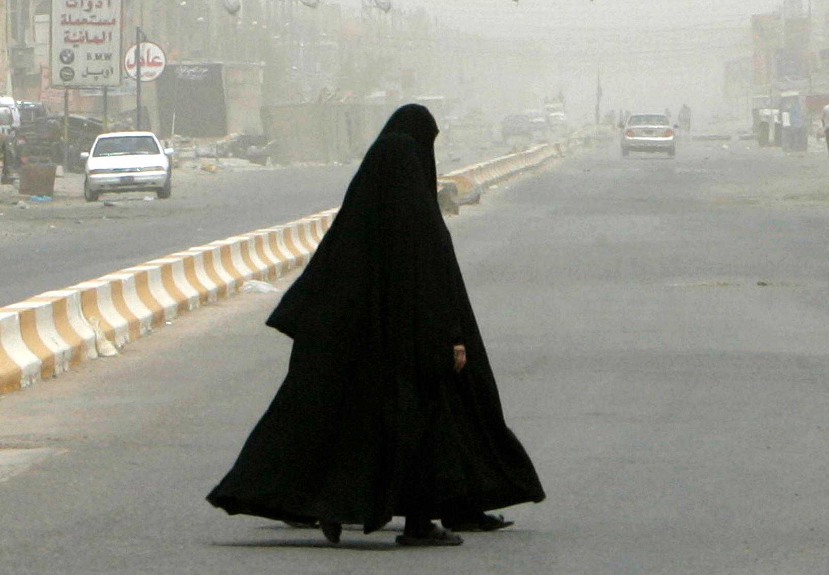 Women walk on a quiet and haze-covered street in the Amil district of Baghdad, July 8, 2007.