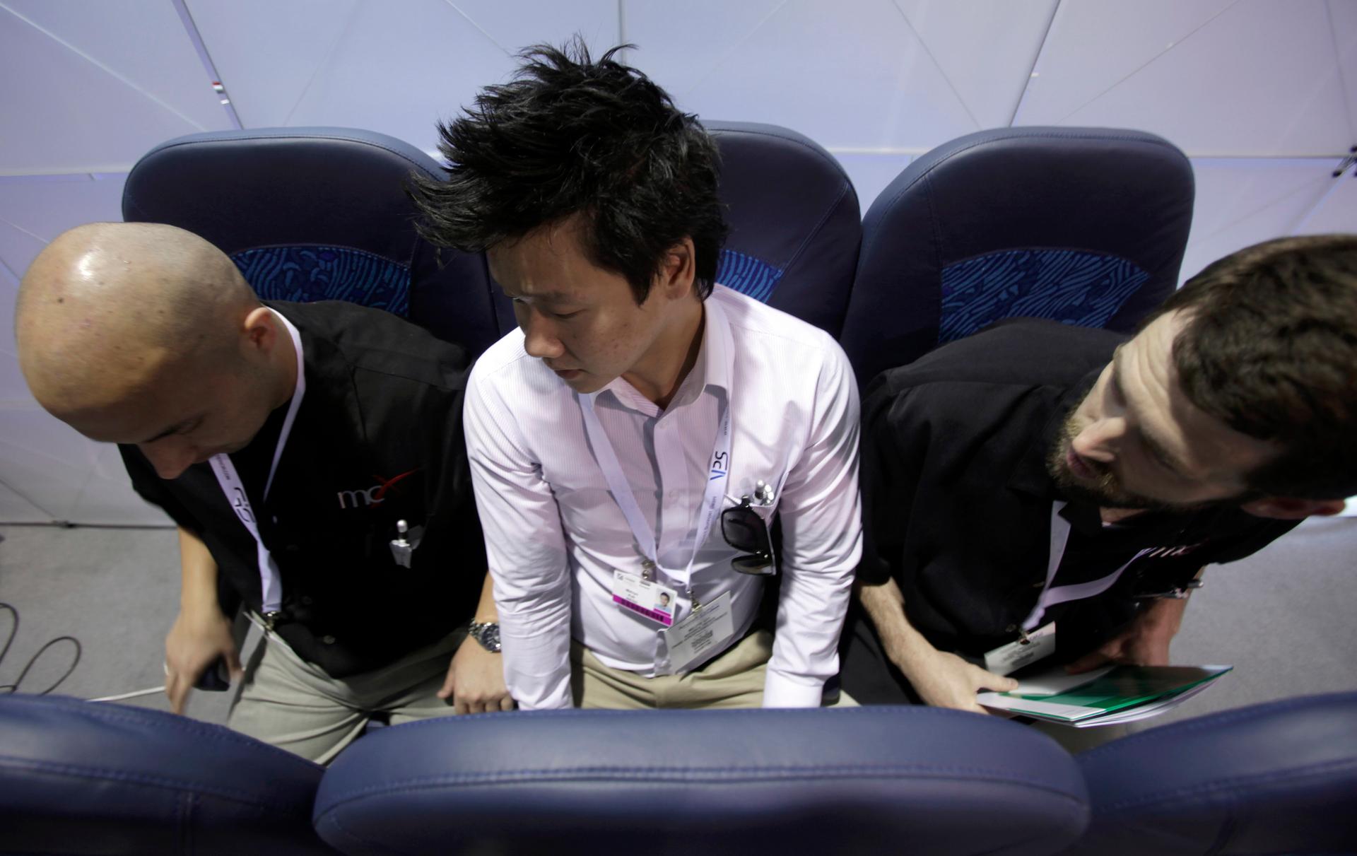 Melvyn Koh, at center, tries out Italian company Aviointeriors' aircraft "standing seat" which has 23 inches of legroom instead of the current economy class average of 30 inches.