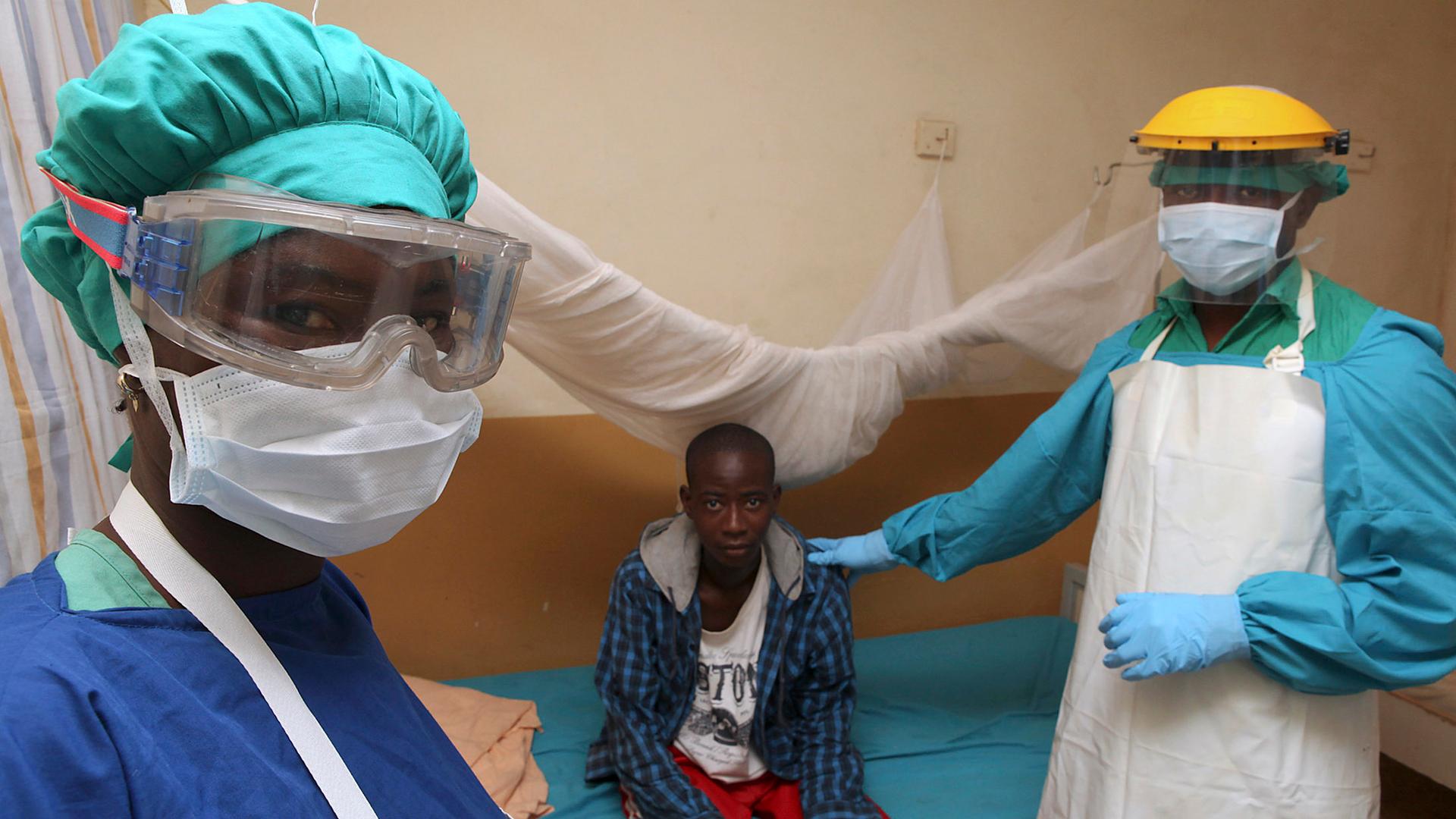 Sierra Leonean nurse Veronica Koroma (left) and doctor Donald Samuel Grant (right) stand by a patient in the Lassa fever ward at Kenema Government Hospital in February, 2011