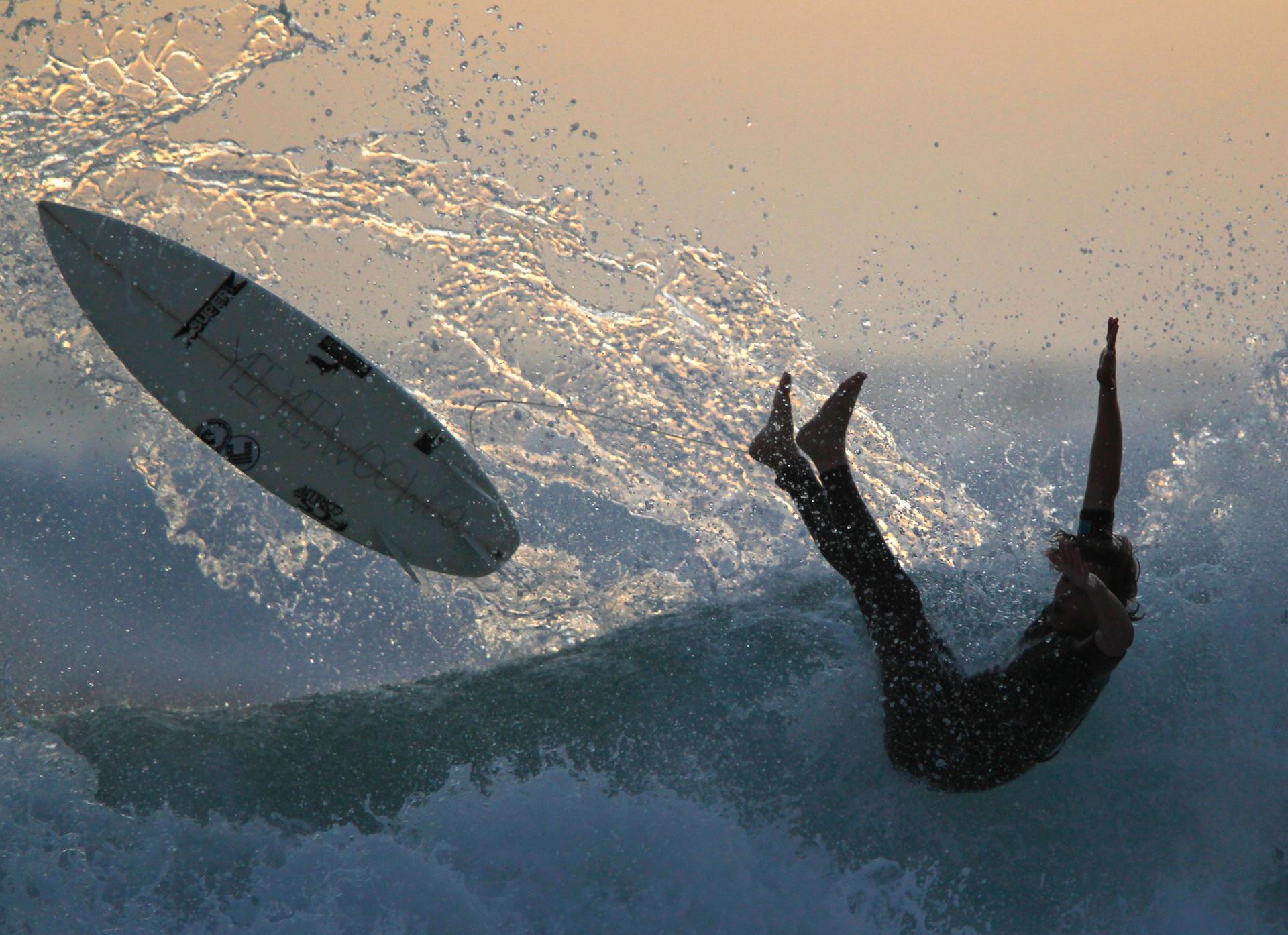 A surfer falls from his board while riding after sunset in Cardiff, California.