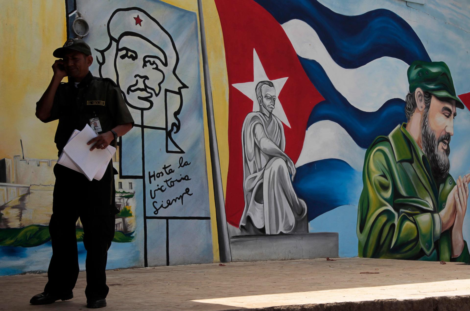 Man makes cell phone call in front of Cuban independence mural in Havana in 2013.