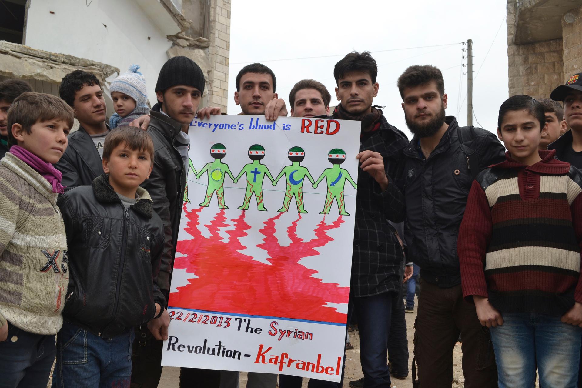 Syrian demonstrators pose with a sign in Kafr Nabl, near Idlib.