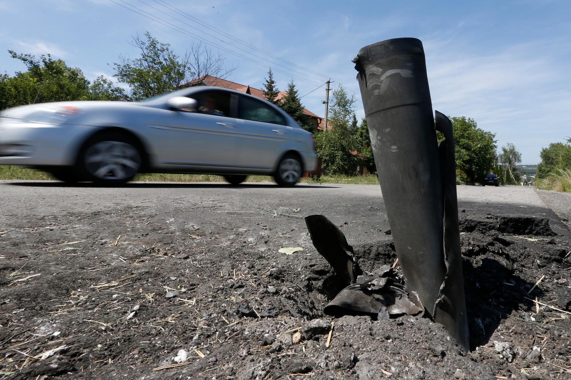 A car drives past the remains of a spent ammunition on the suburbs of Donetsk, Tuesday. Intense fighting between Ukrainian troops and pro-Russian rebels in eastern Ukraine killed dozens of civilians, soldiers and rebels, as Kiev pressed on with an offensi