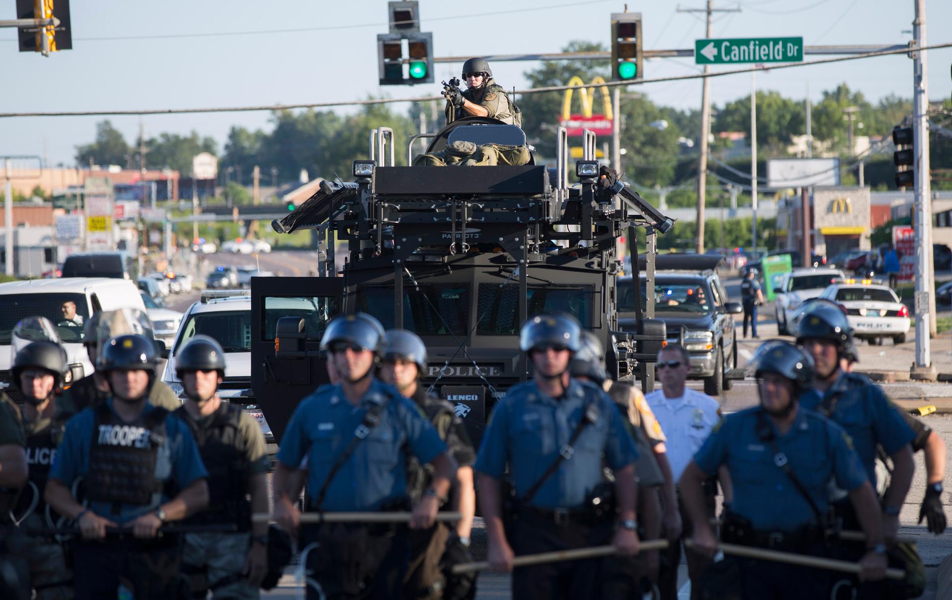 Riot police stand guard as demonstrators protest the shooting death of teenager Michael Brown in Ferguson, Missouri August 13, 2014.