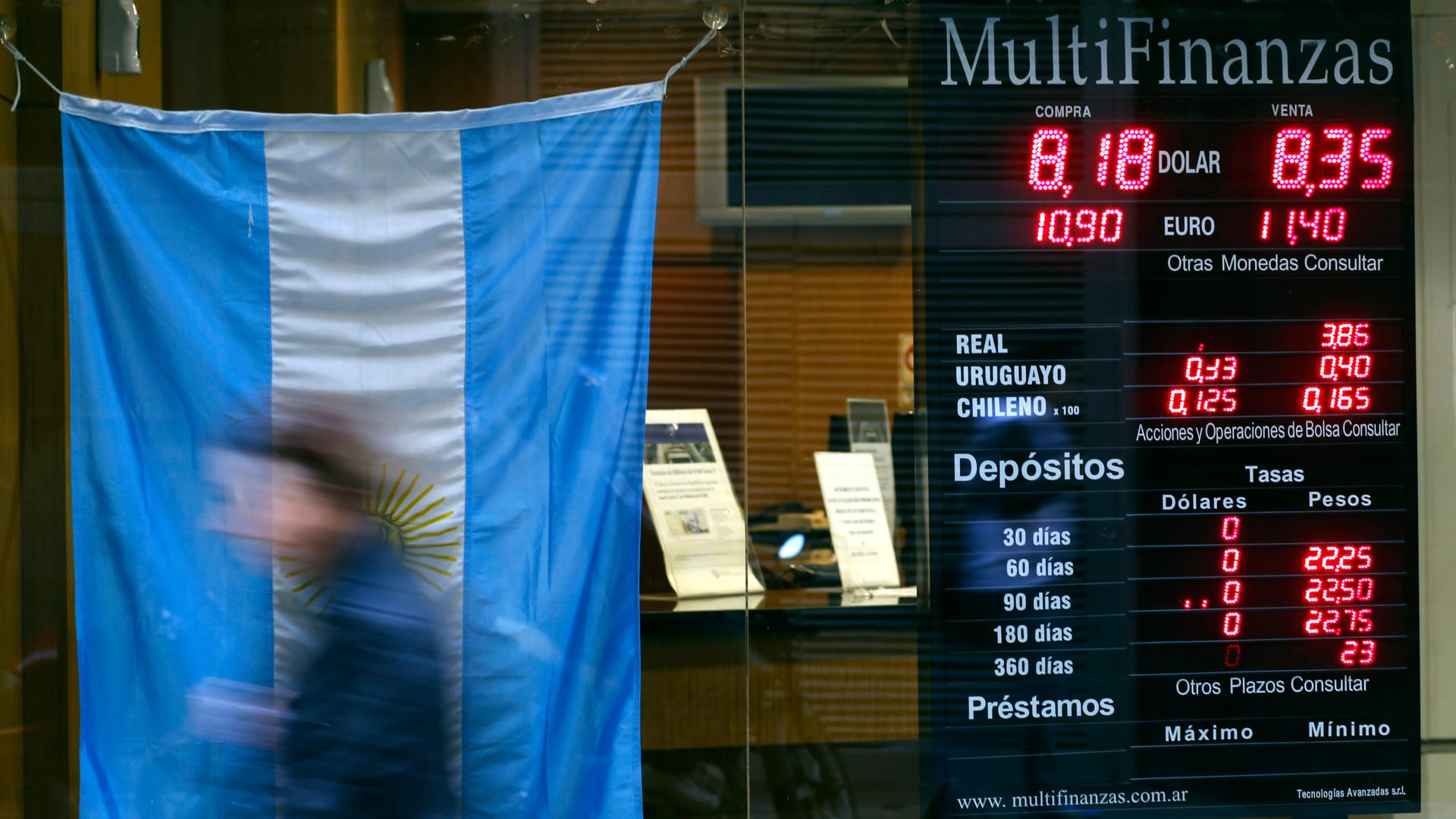 A woman walks past a currency exchange store with an Argentine national flag on display in Buenos Aires' financial district on August 14, 2014