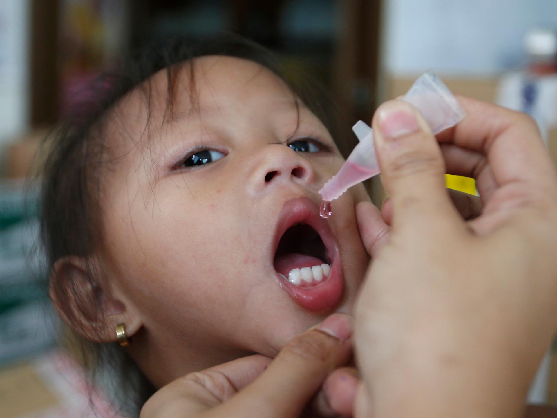 A girl receives anti-measles vaccination drops in Manila, the capital of the Philippines. Mass national vaccination campaigns against measles and polio are common in much of the developing world.