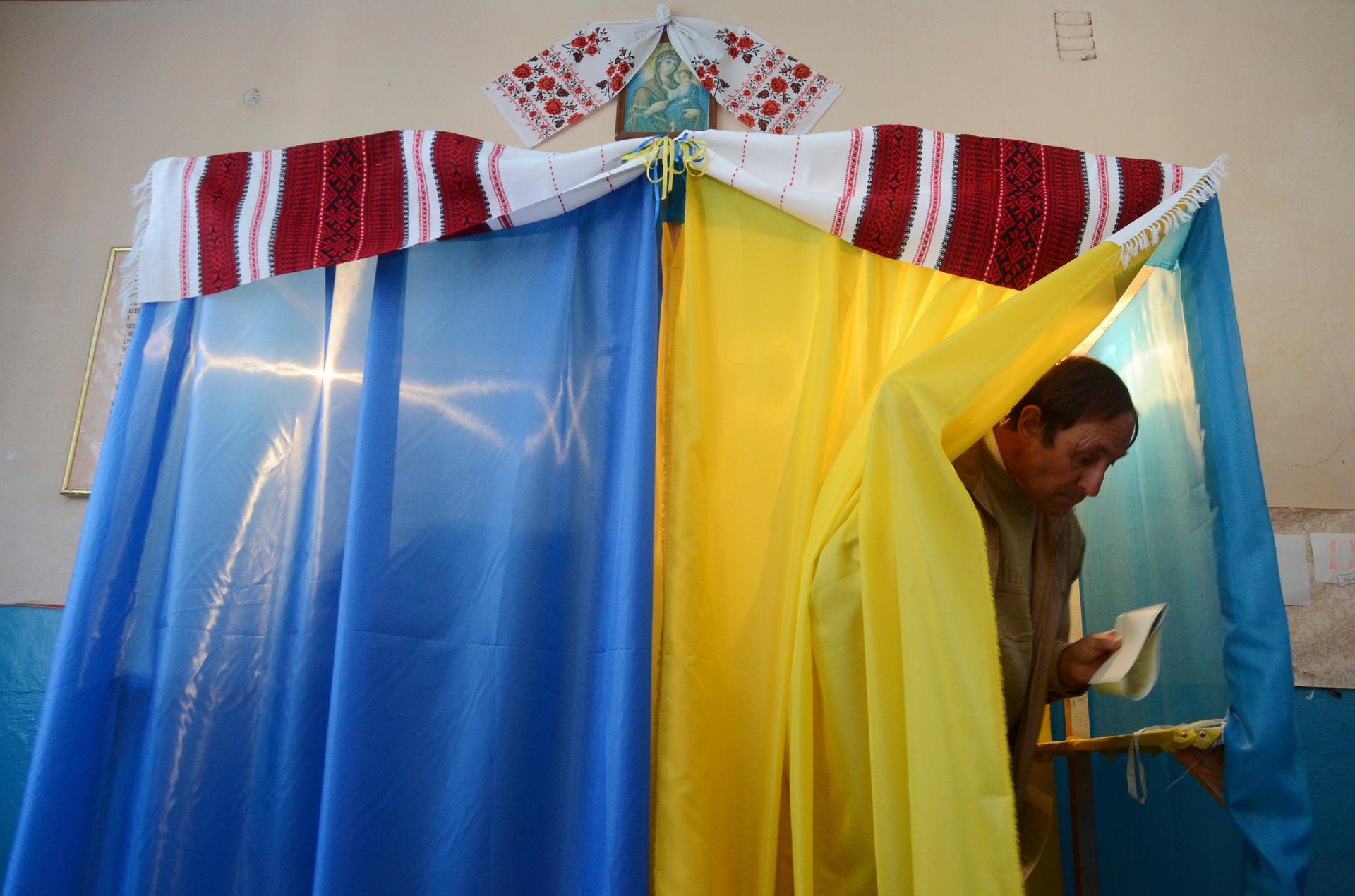 A man walks out of a voting booth at a polling station during a parliamentary election in the village of Fiina near Lviv, on October 26, 2014.