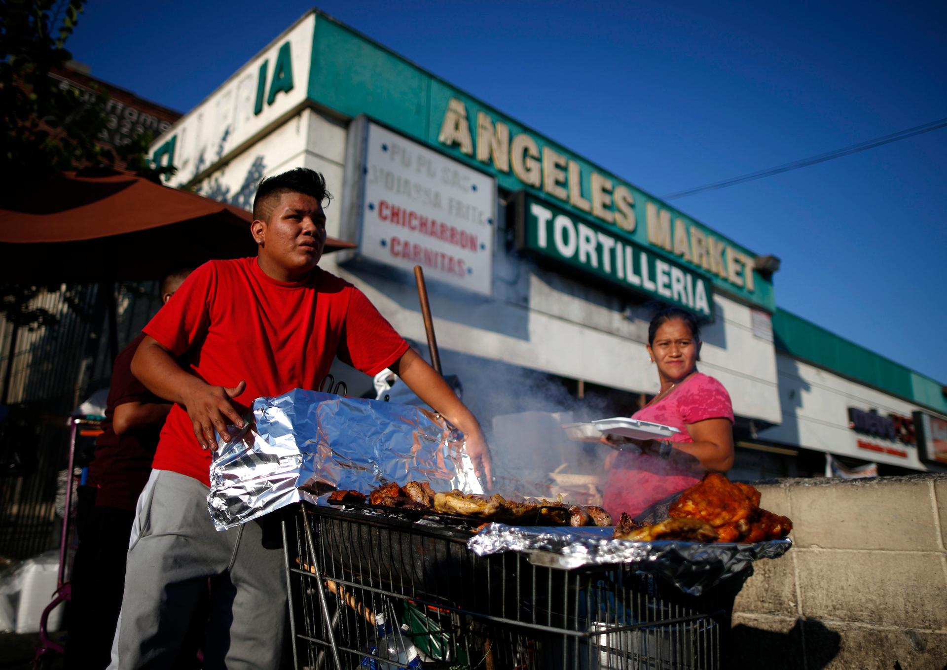 A man cooks meat in a shopping cart in the Westlake area of Los Angeles, home to many Mexican and Central American migrants, California August 6, 2014.