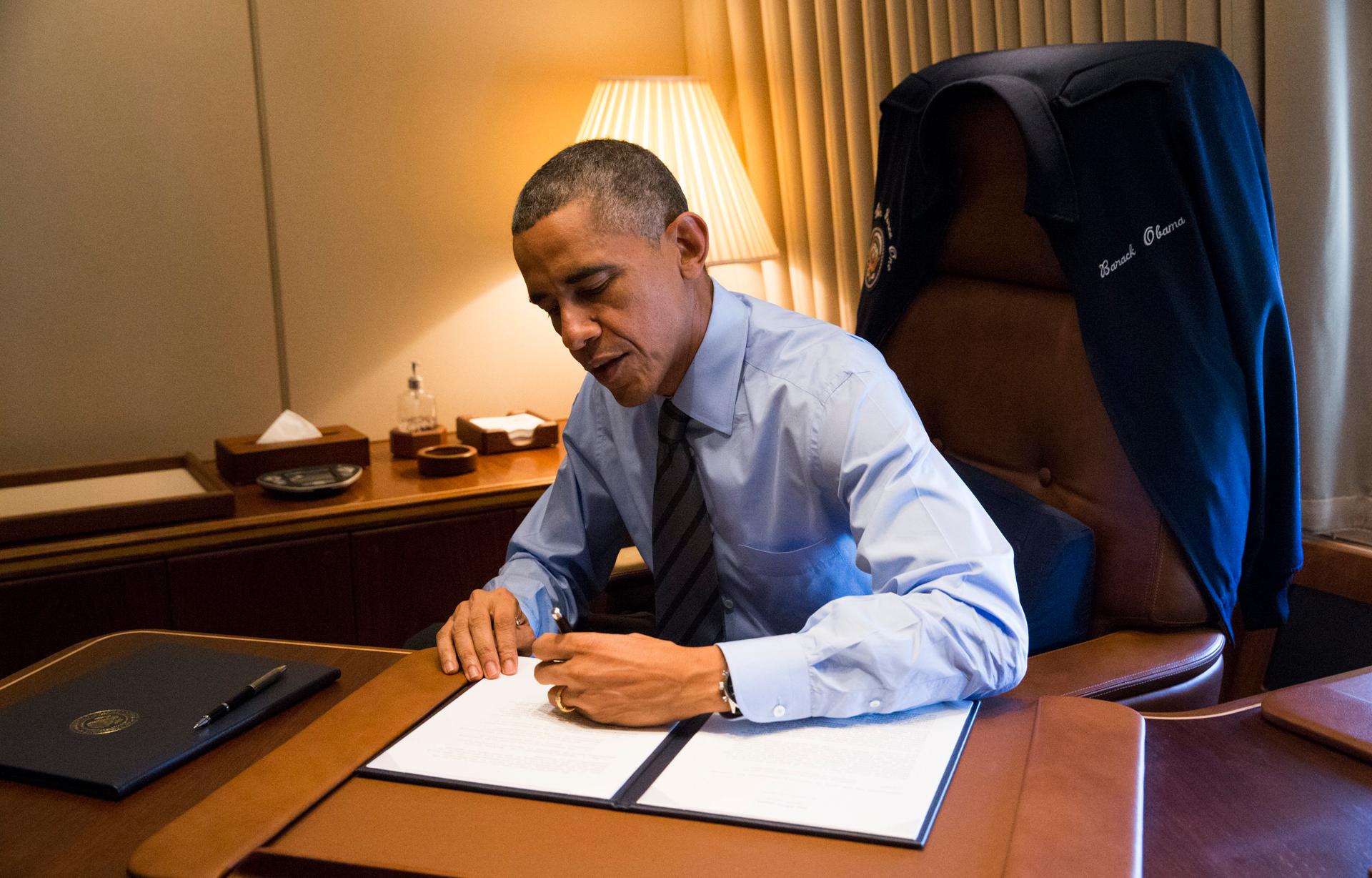 President Barack Obama signs two Presidential Memoranda associated with his Executive Actions on immigration aboard Air Force One on November 21, 2014.