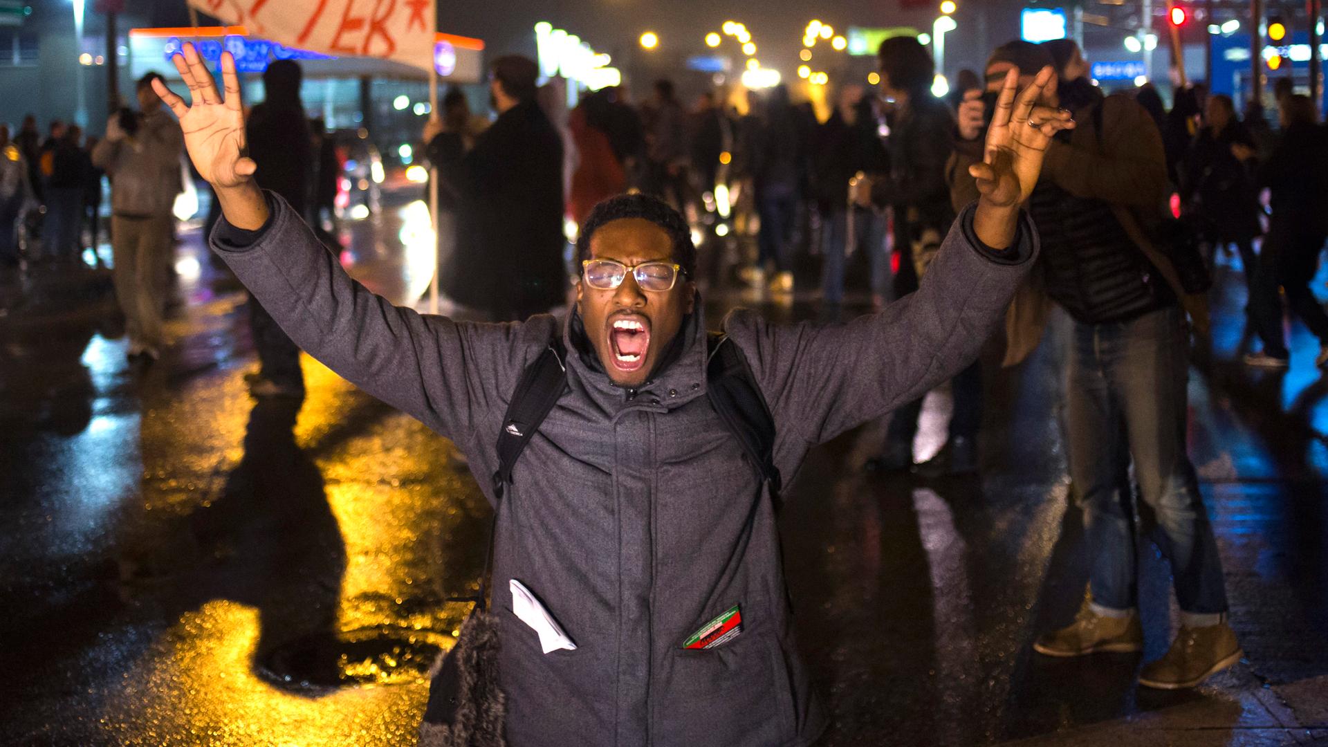 A protester shouts with both his hands in the air while marching through a suburb of St. Louis, Missouri, on November 23, 2014.