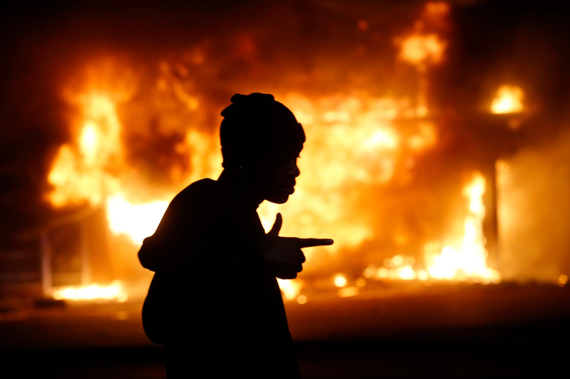A man walks past a burning building during rioting after a grand jury returned no indictment in the shooting of Michael Brown in Ferguson, Missouri.