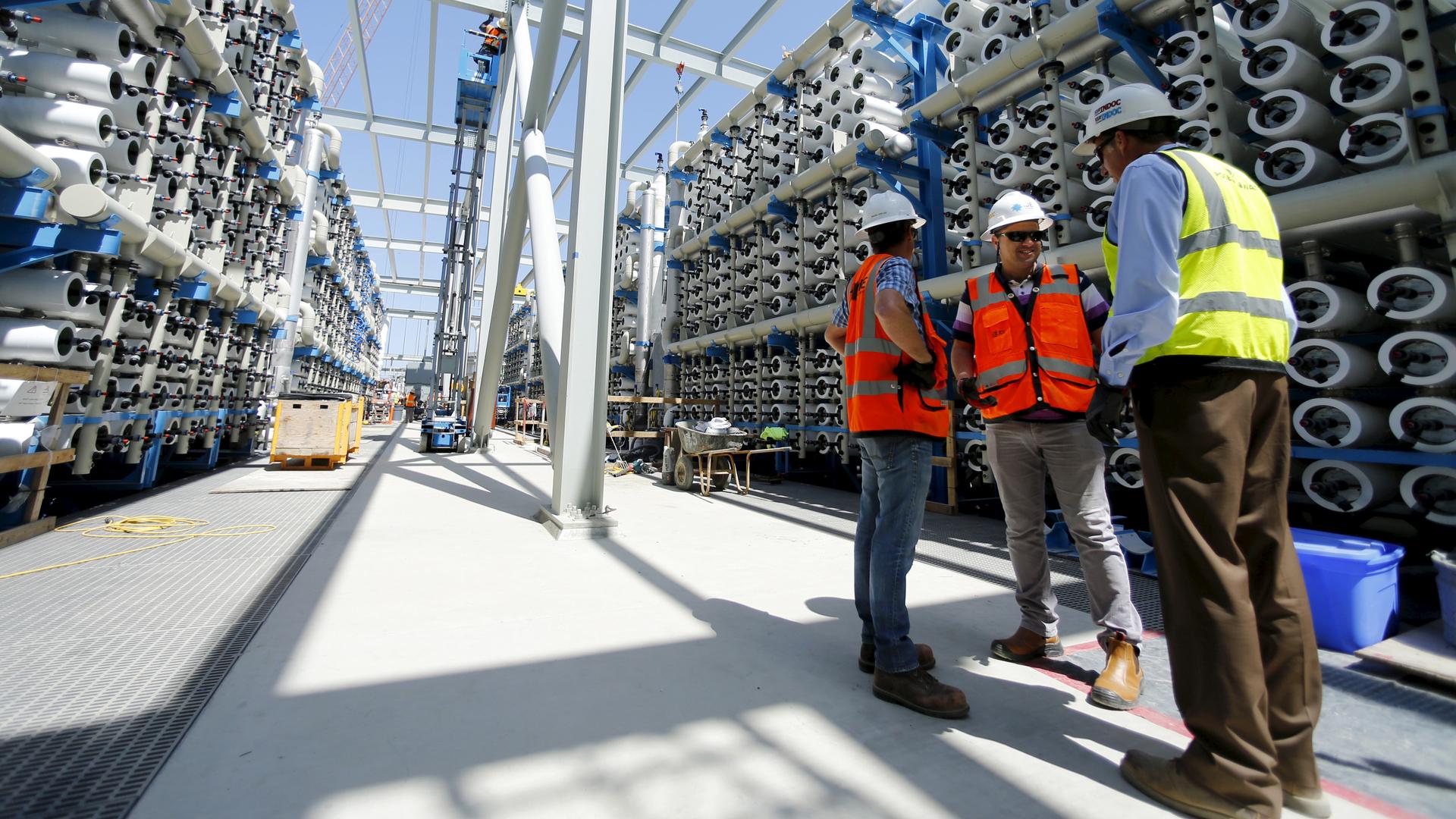 Poseidon Water employees stand between rows of reverse osmosis filters at the Western Hemisphere's largest seawater desalination plant, currently under construction in Carlsbad, California.