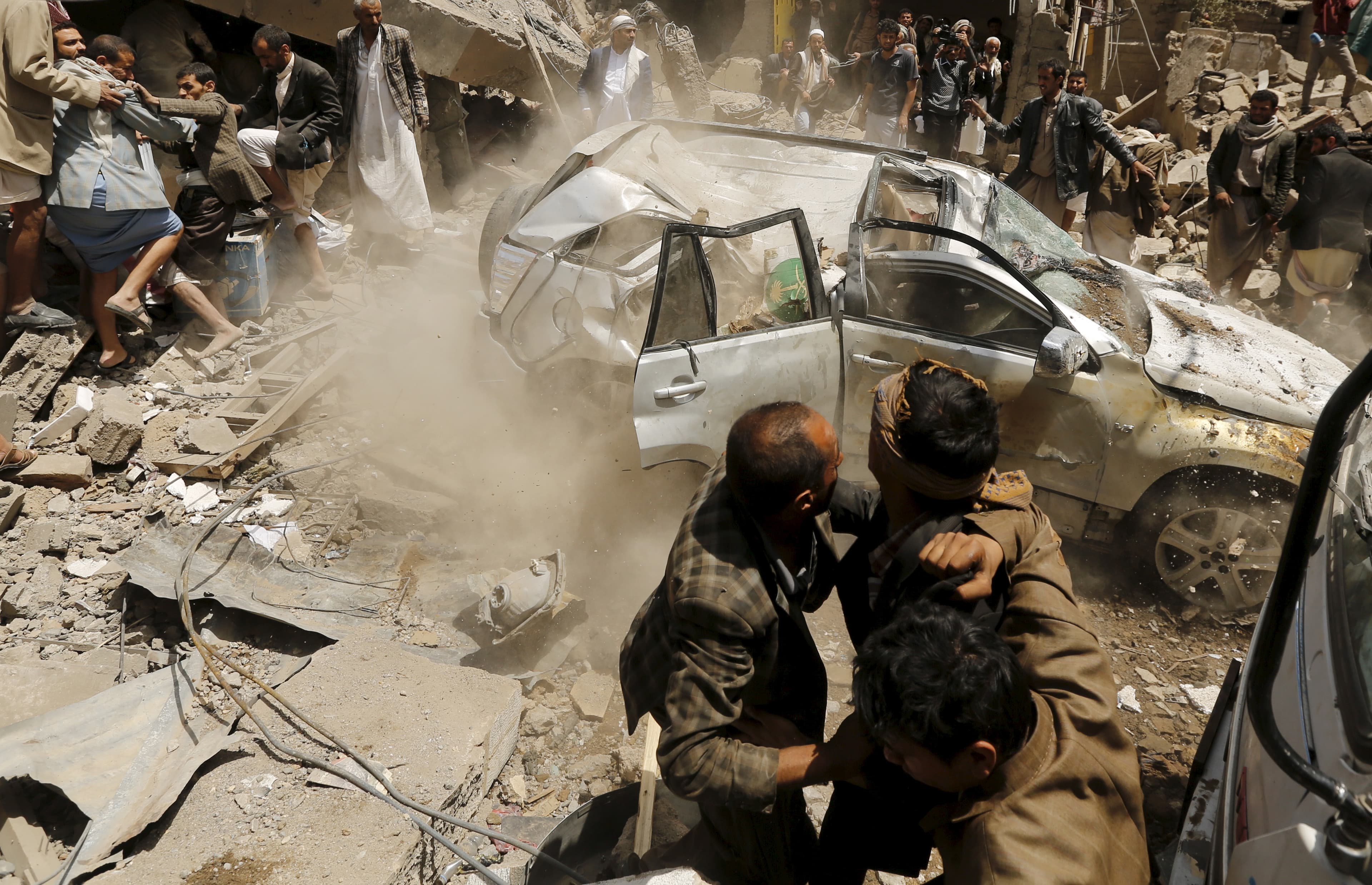 A car falls as it is being lifted by a crane at the site of a Saudi-led air strike in Yemen's capital Sanaa