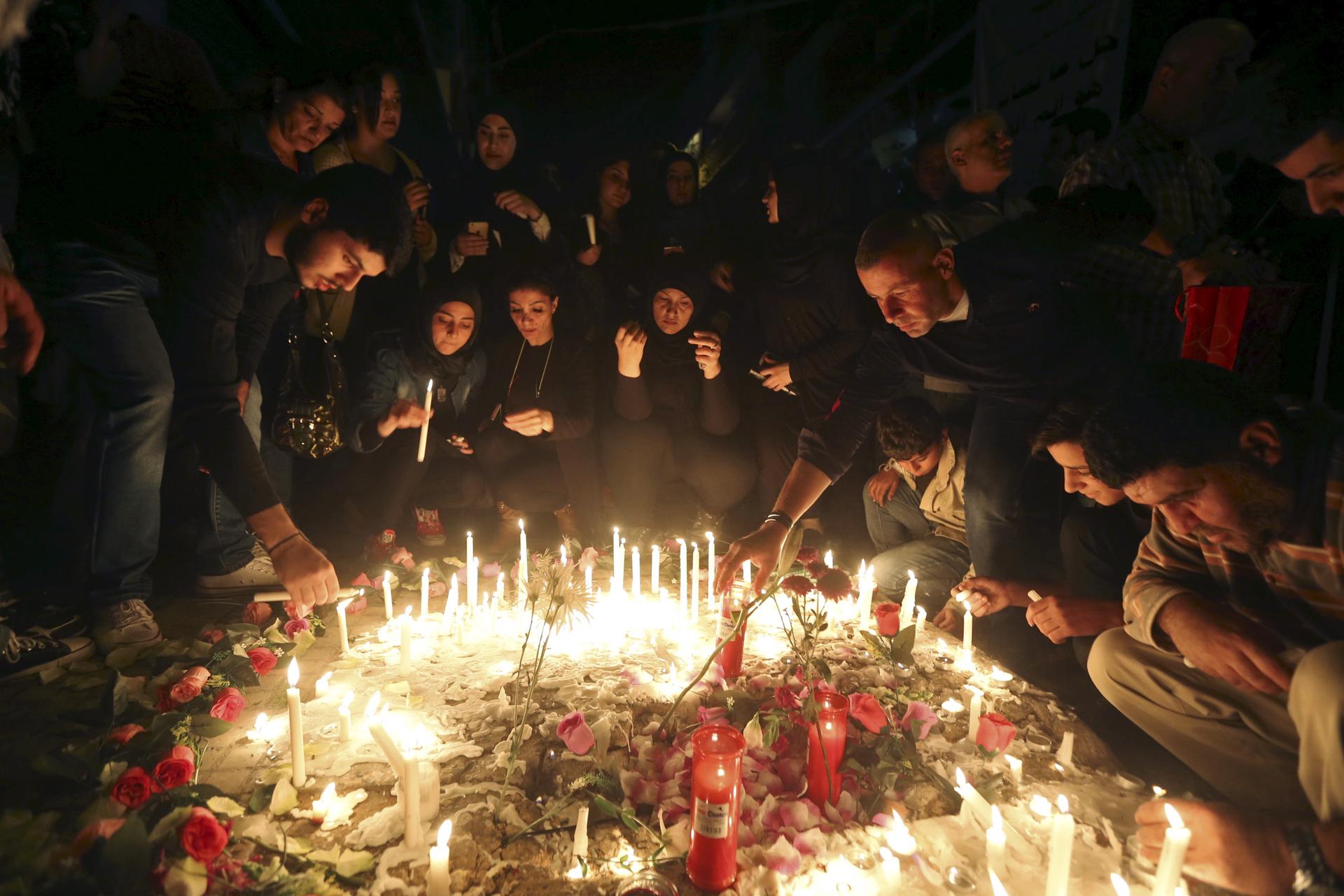 Beirut residents light candles during a vigil at the site of the two explosions that occurred on Thursday in the southern suburbs of the Lebanese capital Beirut,
