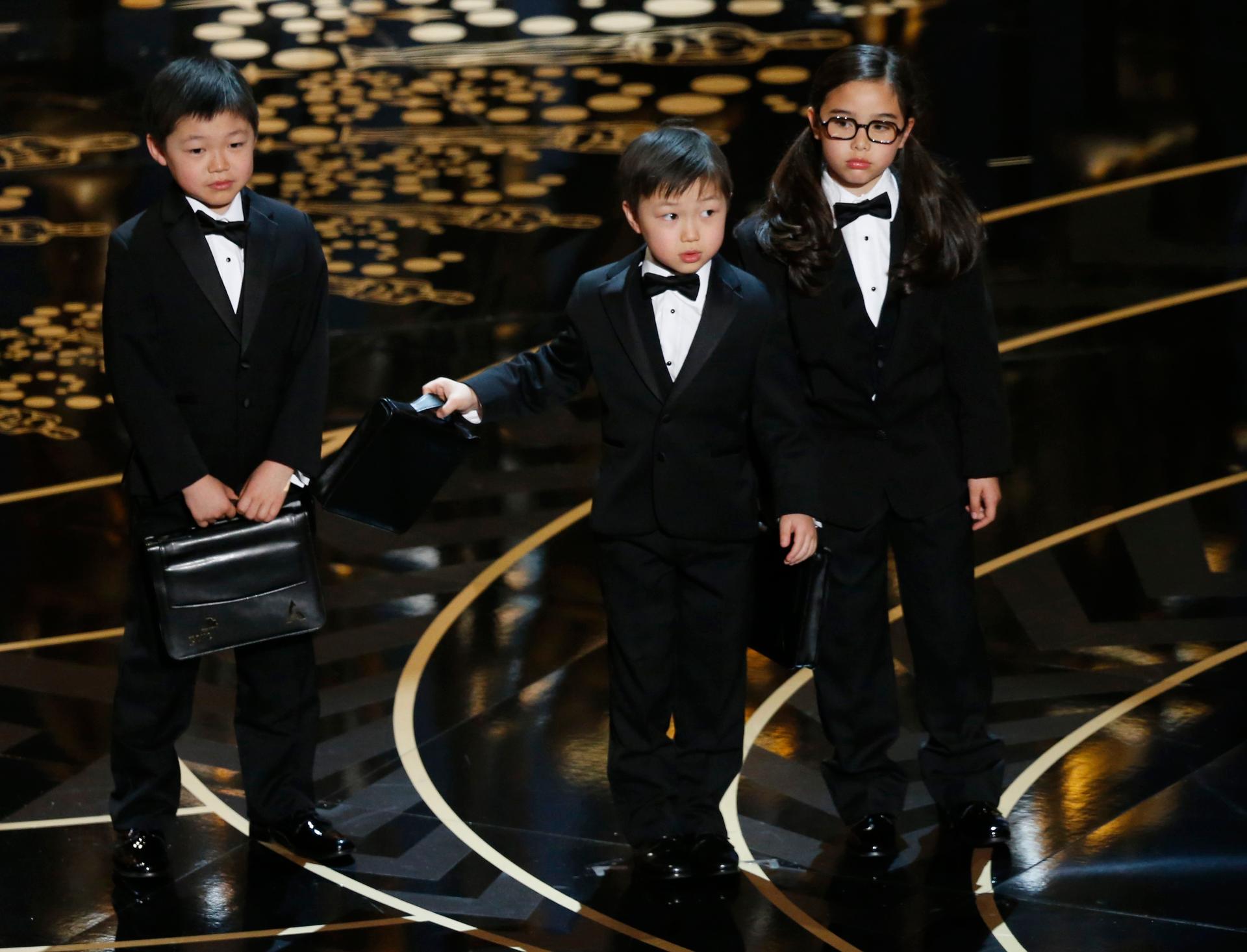 Three children in tuxedos on stage at the Oscars