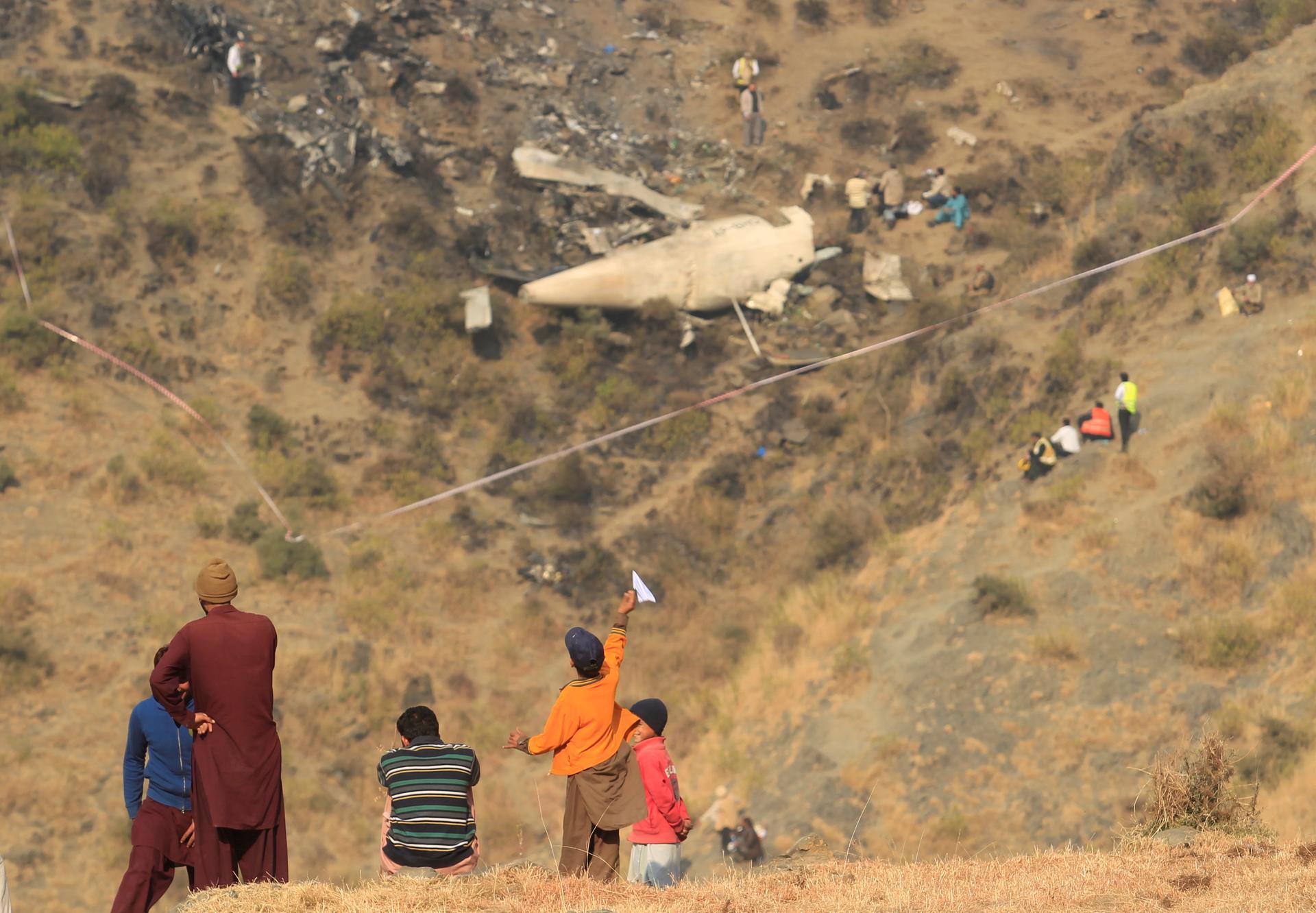 A boy plays with a paper plane near the site of a plane crash in the vilage of Saddha Batolni near Abbotabad, Pakistan December 8, 2016.