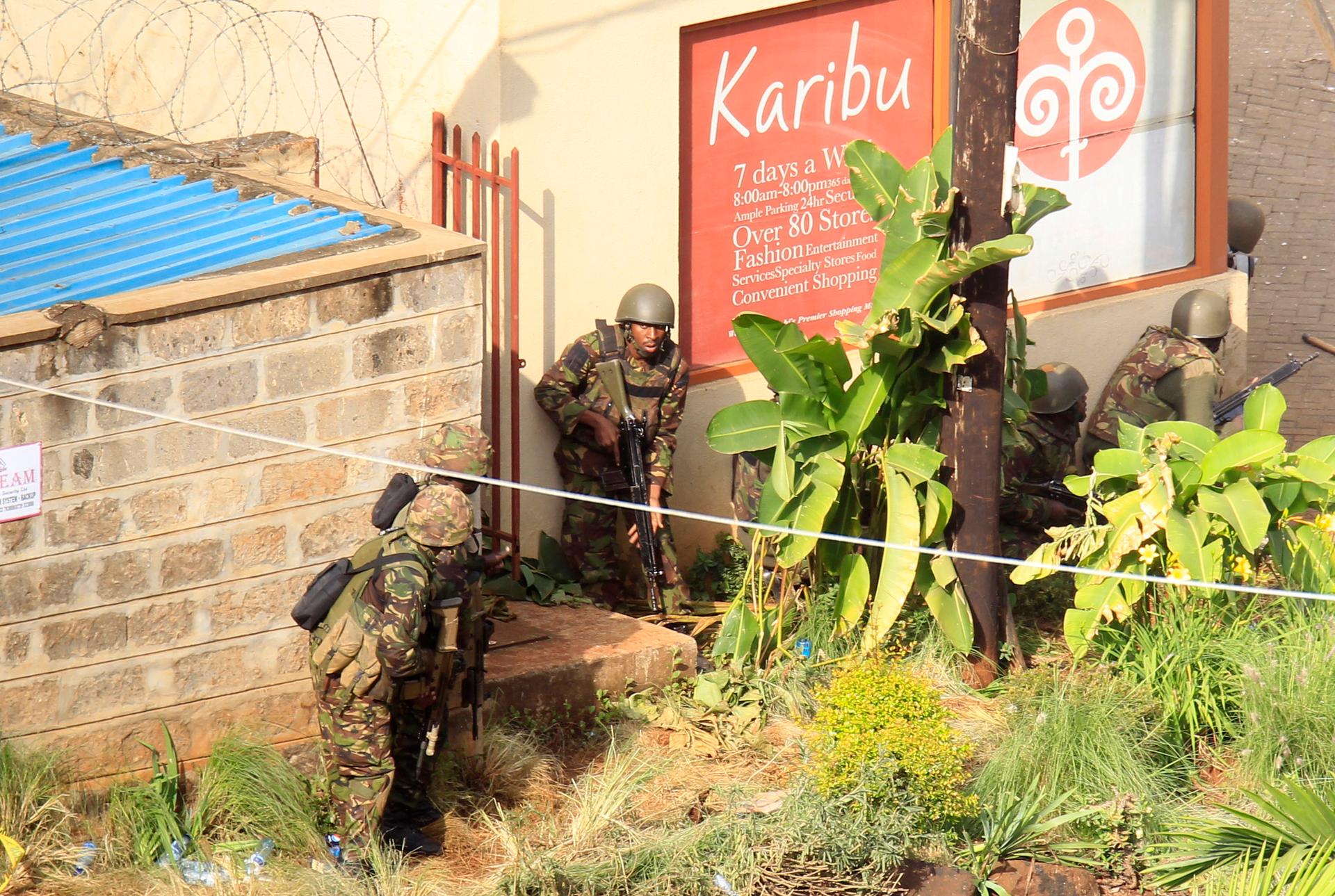Kenyan soldiers take cover behind walls near the Westgate shopping centre after an exchange of gunfire inside the Westgate mall in Nairobi, Monday.