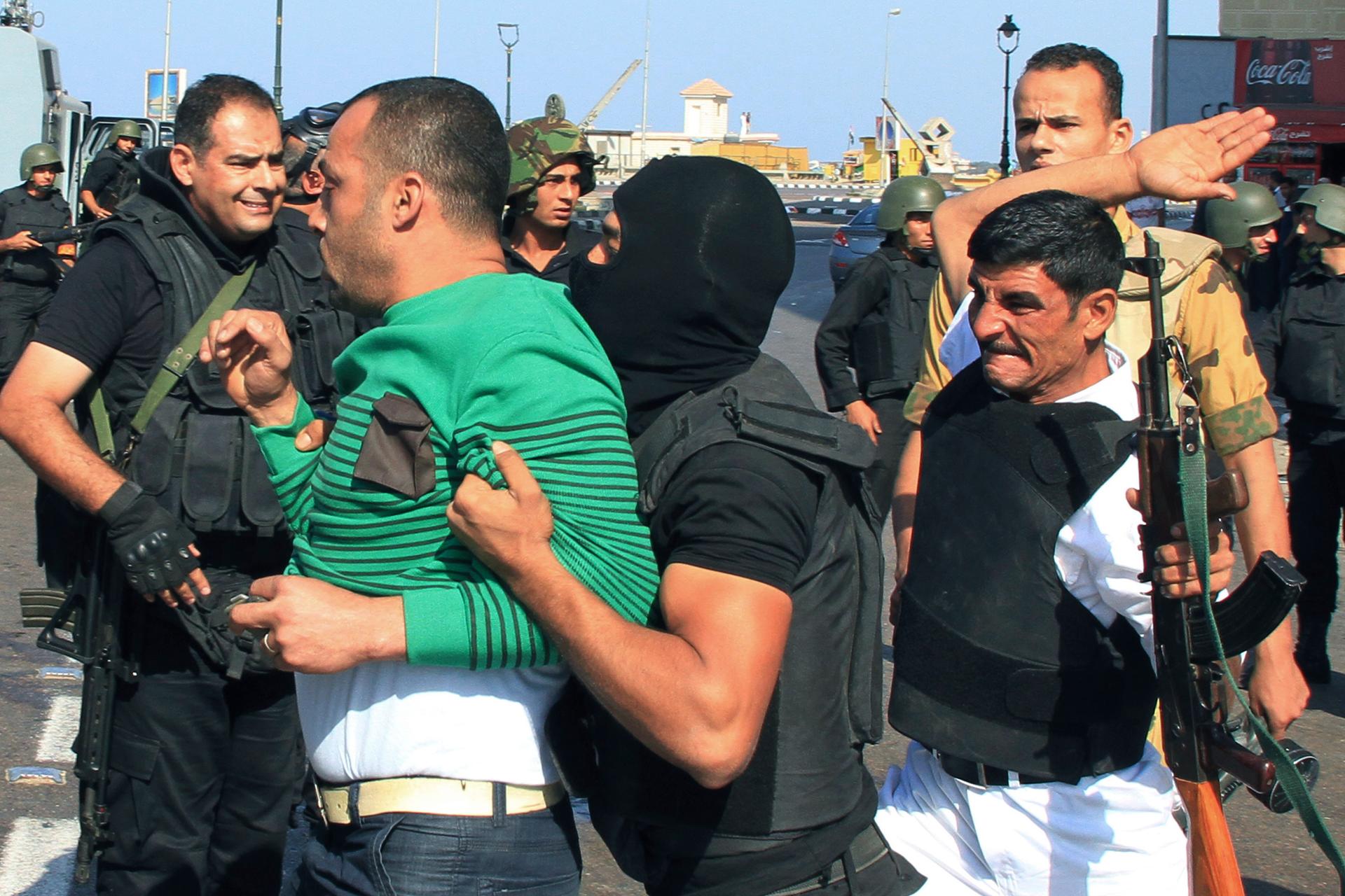 Security forces arrest a pro-Mursi protester during clashes